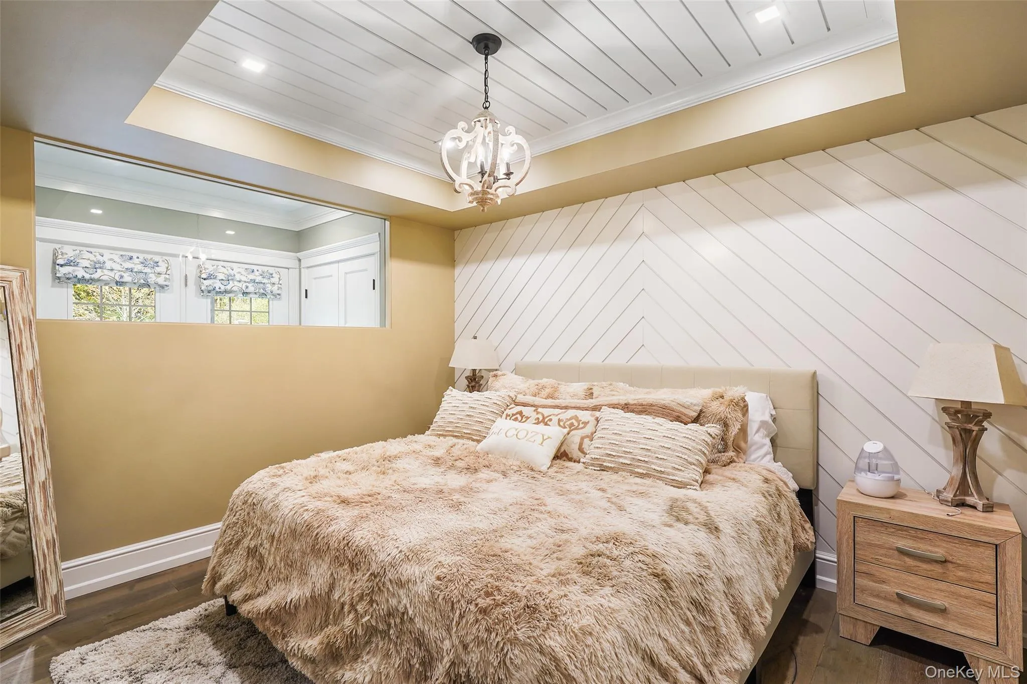 Bedroom with a raised ceiling, ornamental molding, dark wood-style flooring, a chandelier, and wood ceiling Bedroom with a raised ceiling, ornamental molding, dark wood-style flooring, a chandelier, and wood ceiling
