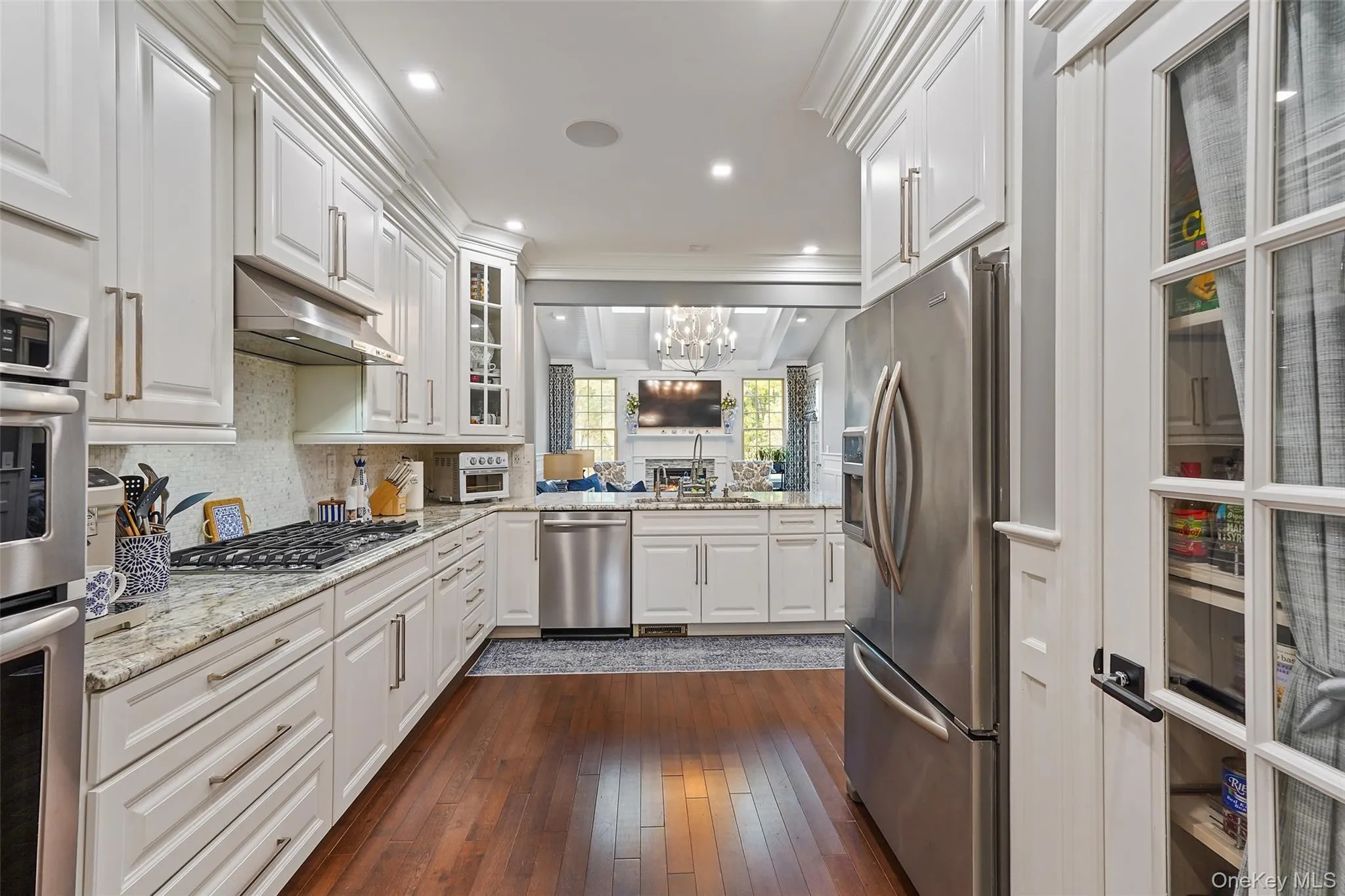 Kitchen with glass insert pantry, white cabinetry, light stone counters, appliances with stainless steel finishes, and recessed lighting Kitchen with glass insert pantry, white cabinetry, light stone counters, appliances with stainless steel finishes, and recessed lighting