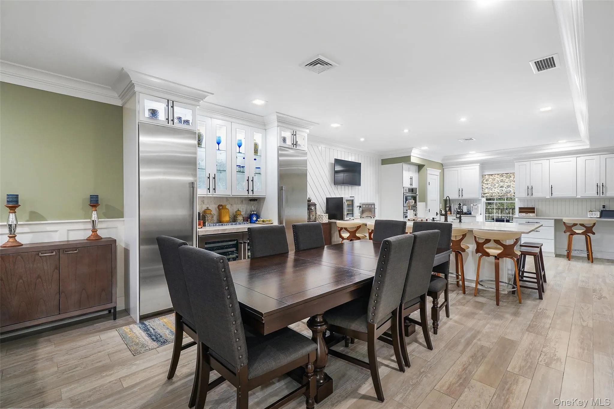 Dining area featuring ornamental molding, light wood-type flooring, recessed lighting, and beverage cooler Dining area featuring ornamental molding, light wood-type flooring, recessed lighting, and beverage cooler