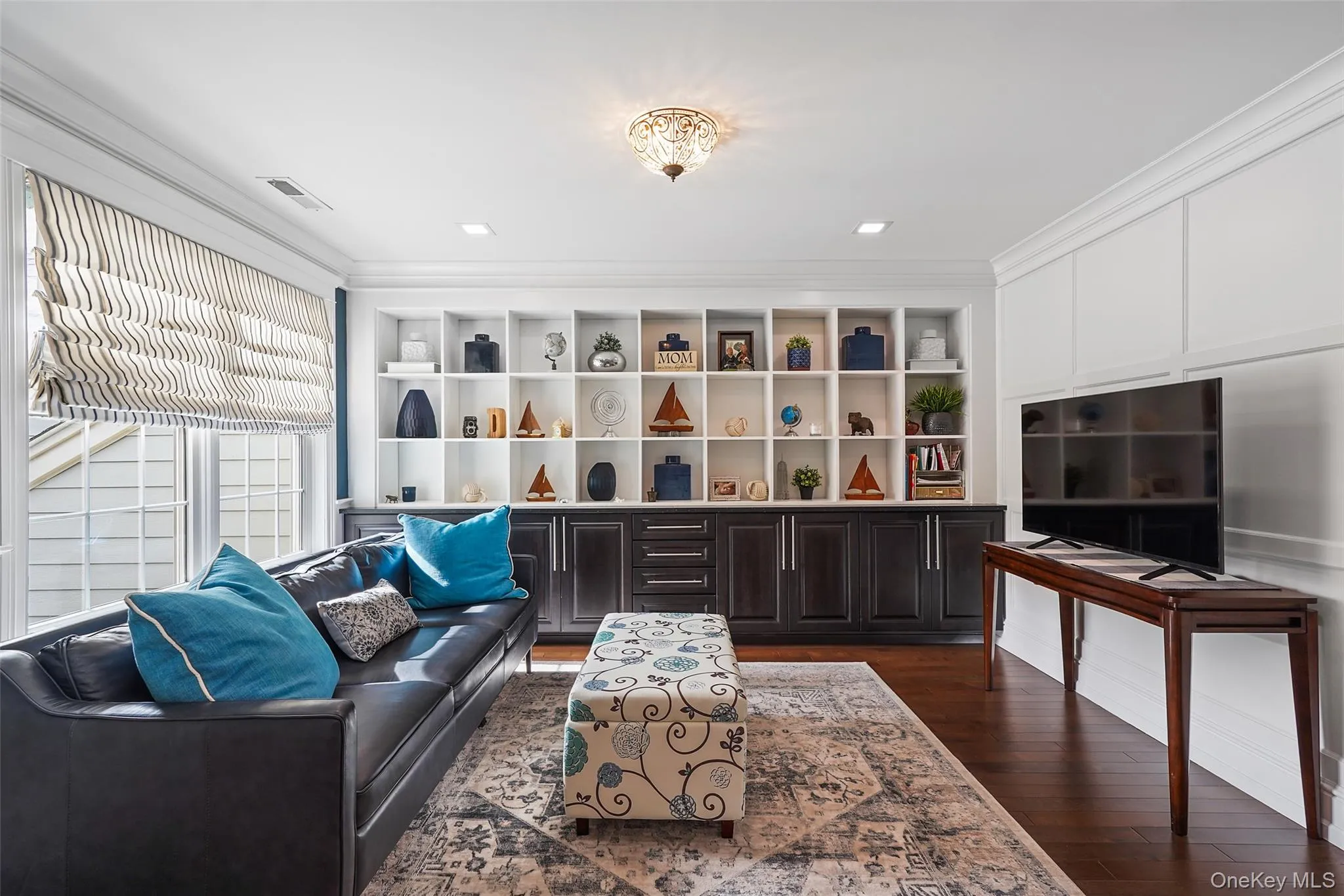 Living area with dark wood finished floors, ornamental molding, and built in features Living area with dark wood finished floors, ornamental molding, and built in features