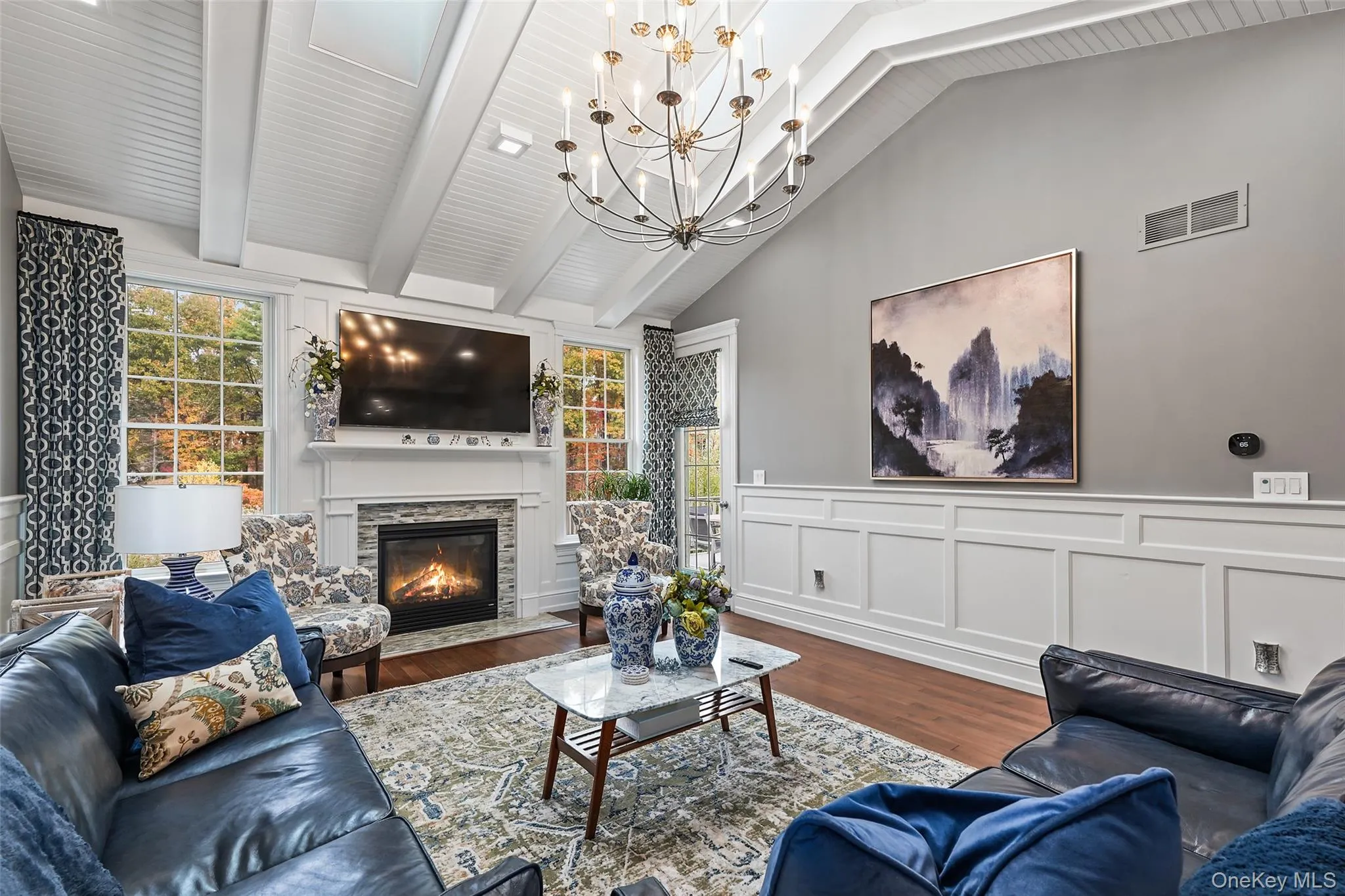 Living room featuring a decorative wall, wood finished floors, a wainscoted wall, a fireplace, and a chandelier Living room featuring a decorative wall, wood finished floors, a wainscoted wall, a fireplace, and a chandelier