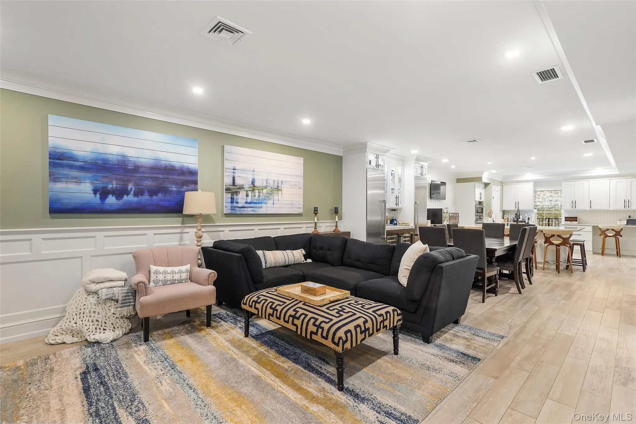 Living room with light wood finished floors, a decorative wall, ornamental molding, a wainscoted wall, and recessed lighting Living room with light wood finished floors, a decorative wall, ornamental molding, a wainscoted wall, and recessed lighting