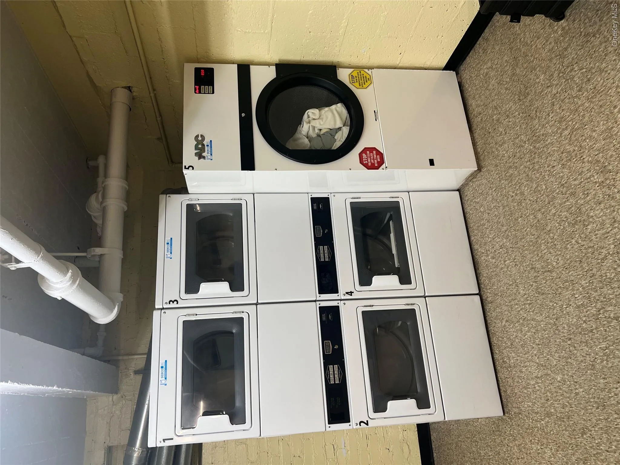 Shared laundry area with stacked washer and dryer, baseboards, and washer and clothes dryer Shared laundry area with stacked washer and dryer, baseboards, and washer and clothes dryer