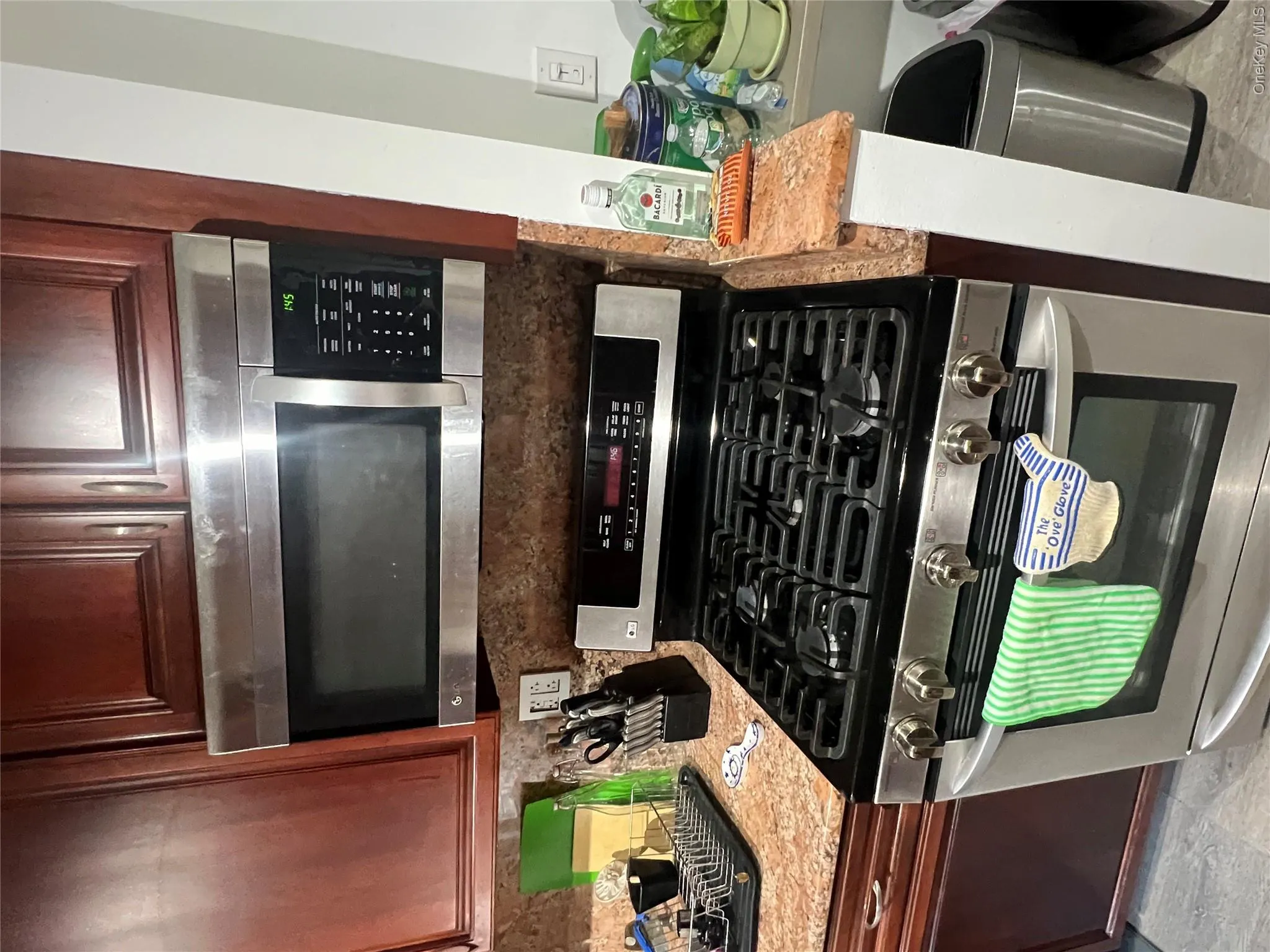 Kitchen with stainless steel gas range oven, light stone counters, and decorative backsplash Kitchen with stainless steel gas range oven, light stone counters, and decorative backsplash