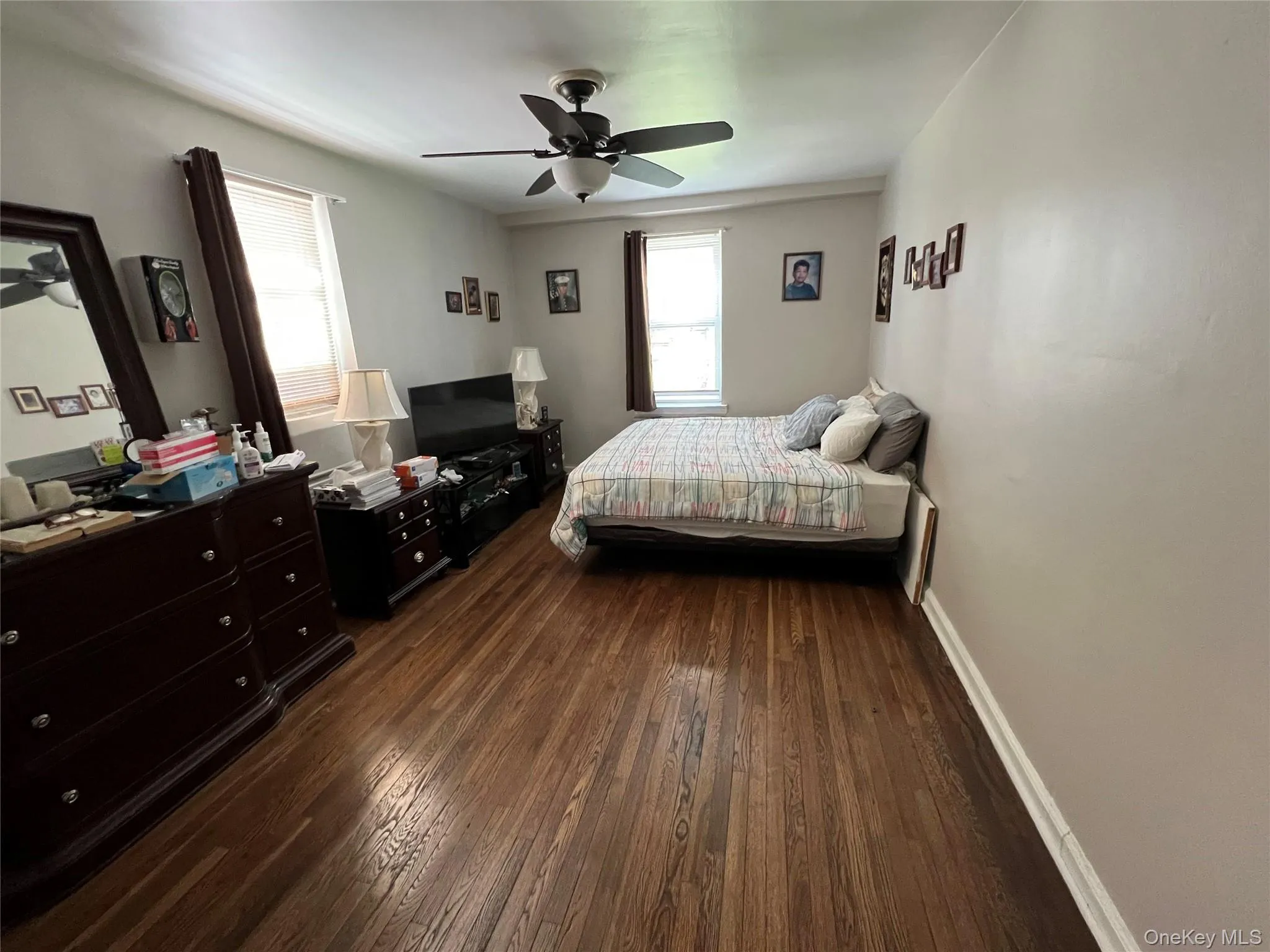 Bedroom featuring a ceiling fan, baseboards, and dark wood-type flooring Bedroom featuring a ceiling fan, baseboards, and dark wood-type flooring