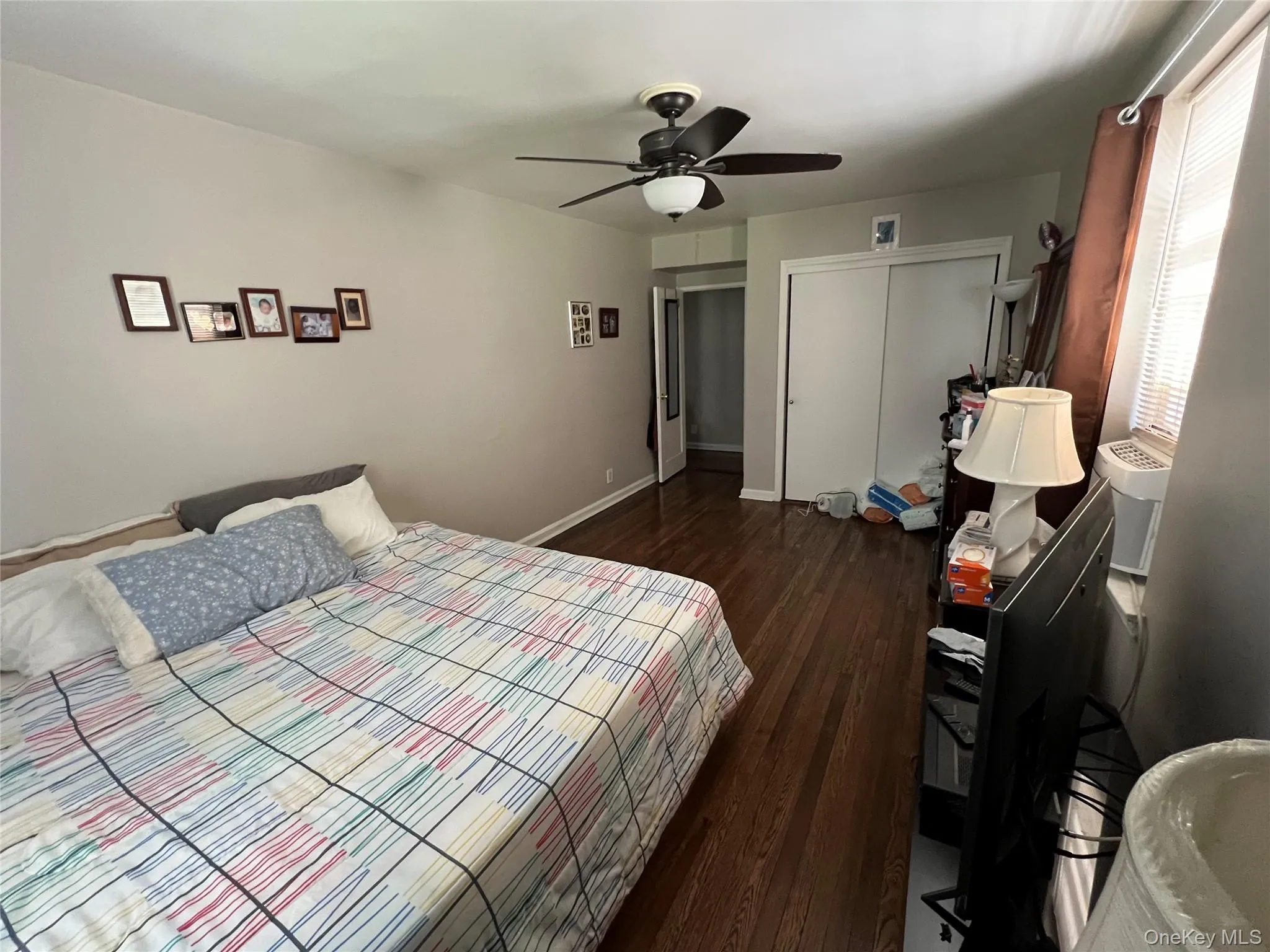 Bedroom with a ceiling fan, baseboards, a closet, and dark wood-style flooring Bedroom with a ceiling fan, baseboards, a closet, and dark wood-style flooring