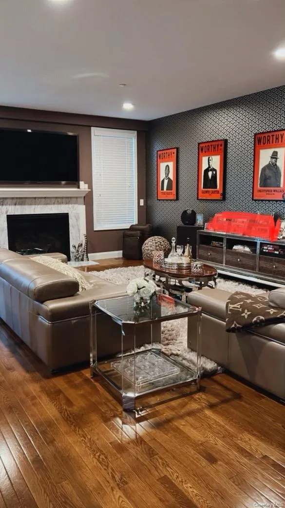 Living room featuring wallpapered walls, a high end fireplace, and dark wood finished floors Living room featuring wallpapered walls, a high end fireplace, and dark wood finished floors