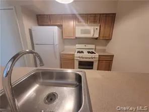 Kitchen with white appliances, light countertops, and brown cabinetry Kitchen with white appliances, light countertops, and brown cabinetry