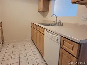 Kitchen featuring light tile patterned floors, white dishwasher, and light countertops Kitchen featuring light tile patterned floors, white dishwasher, and light countertops