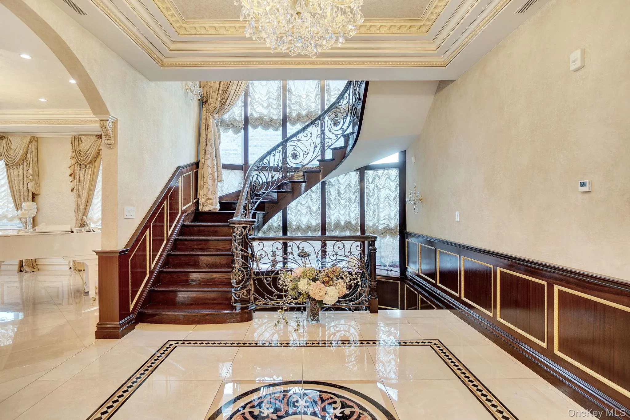 Stairs with inlaid floor details, ornamental molding, arched walkways, a chandelier, and tile patterned floors Stairs with inlaid floor details, ornamental molding, arched walkways, a chandelier, and tile patterned floors