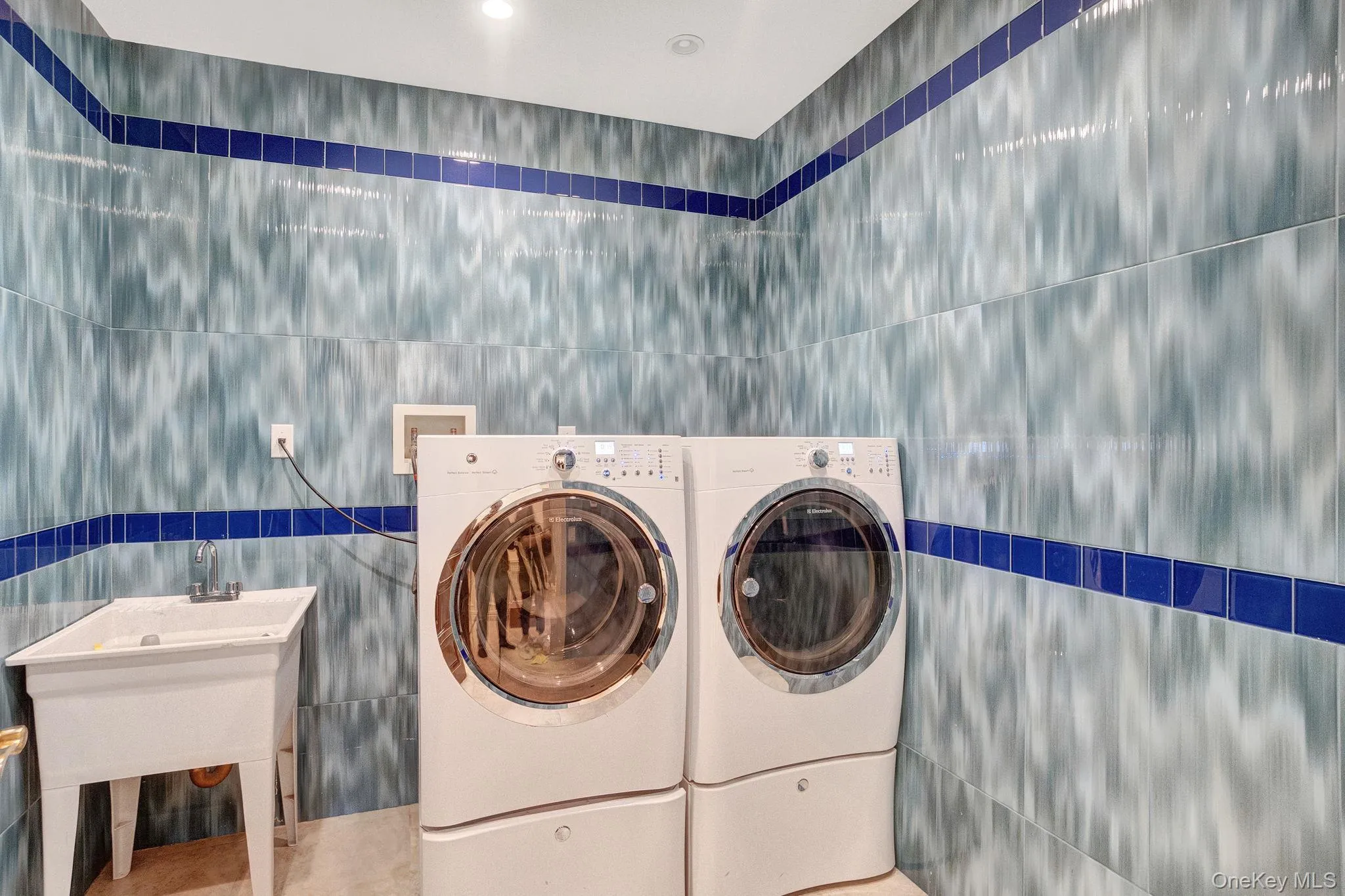 Washroom featuring tile walls and washer and clothes dryer Washroom featuring tile walls and washer and clothes dryer