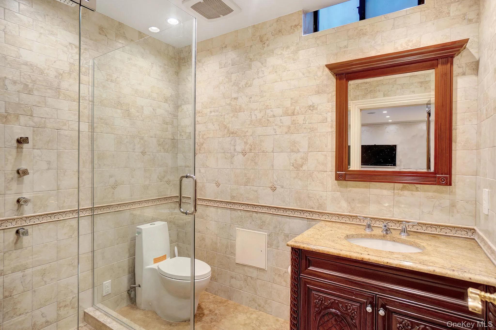 Bathroom with tile walls, vanity, a shower stall, and tile patterned flooring Bathroom with tile walls, vanity, a shower stall, and tile patterned flooring