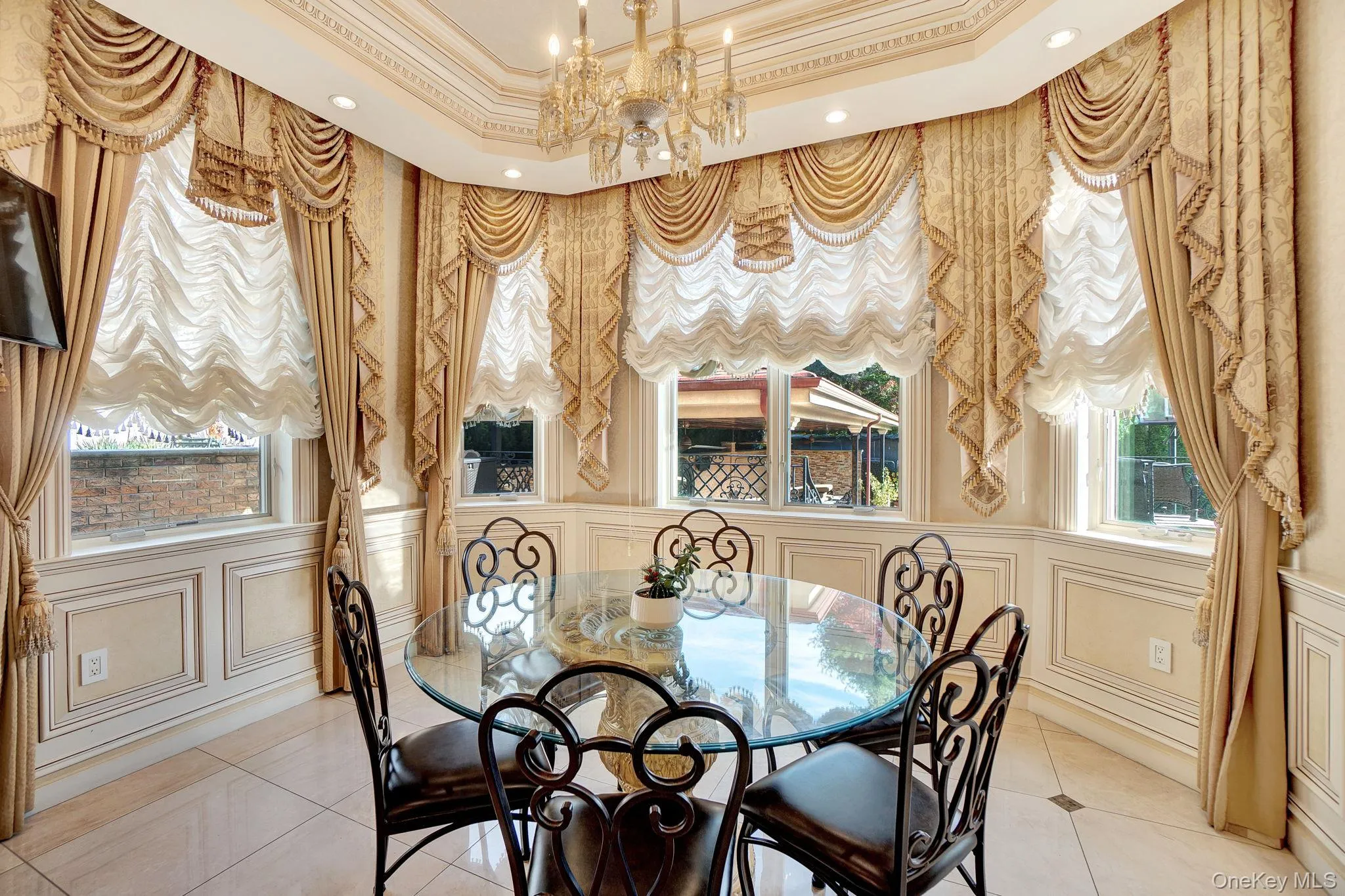 Dining space with a decorative wall, a chandelier, tile patterned flooring, crown molding, and a tray ceiling Dining space with a decorative wall, a chandelier, tile patterned flooring, crown molding, and a tray ceiling