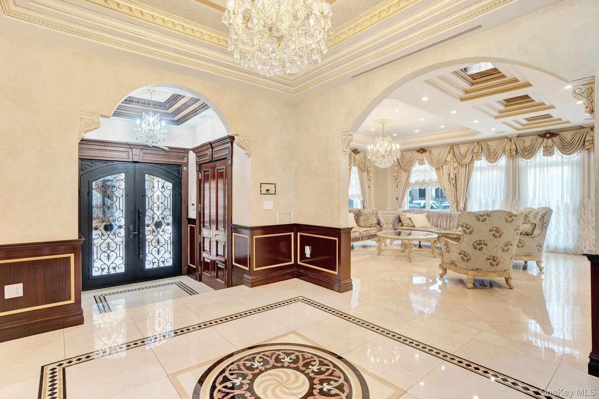 Foyer entrance with inlaid floor details, a chandelier, arched walkways, ornamental molding, and light tile patterned floors Foyer entrance with inlaid floor details, a chandelier, arched walkways, ornamental molding, and light tile patterned floors