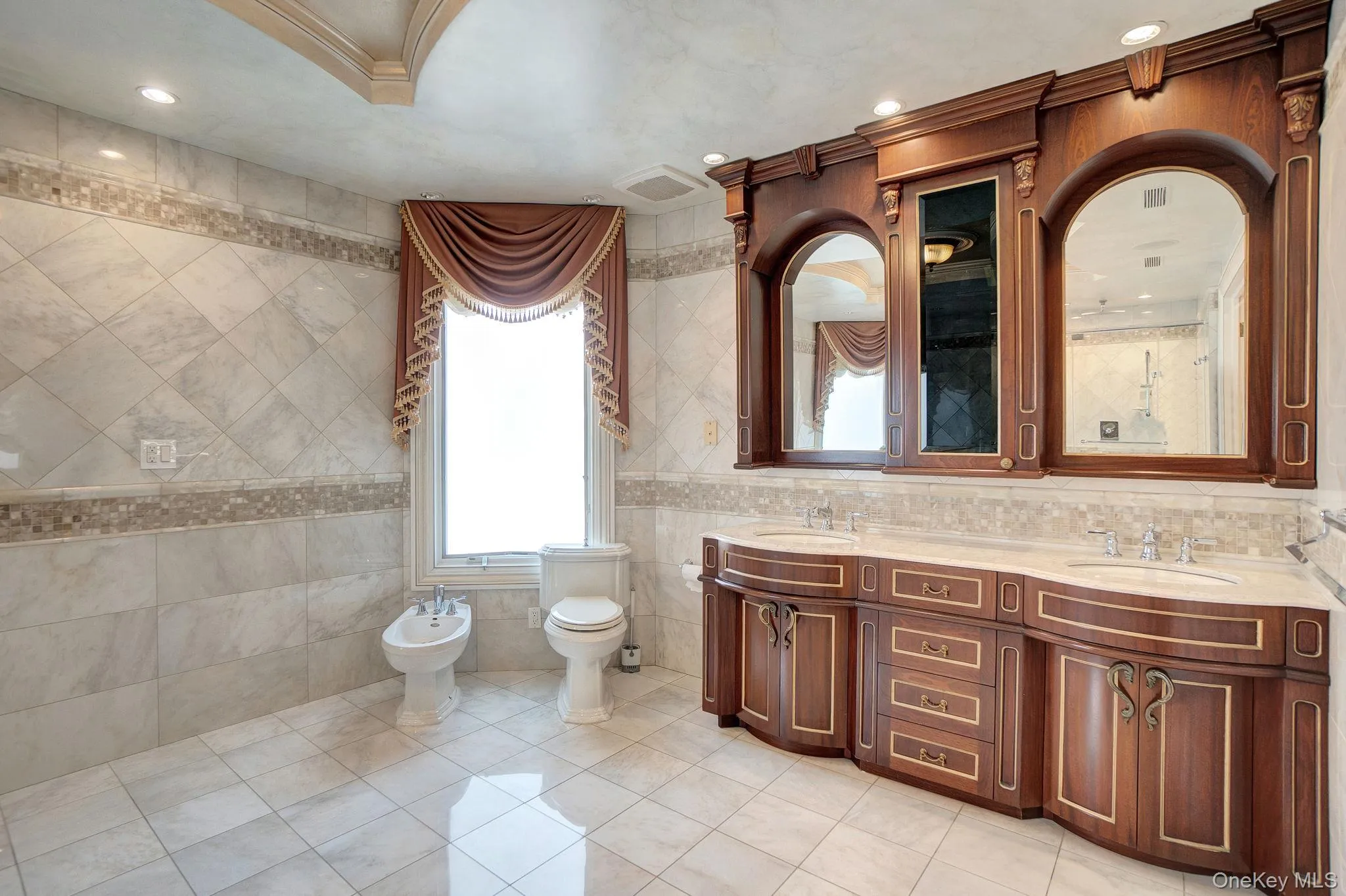 Bathroom featuring tile walls, light tile patterned floors, double vanity, recessed lighting, and a bidet Bathroom featuring tile walls, light tile patterned floors, double vanity, recessed lighting, and a bidet