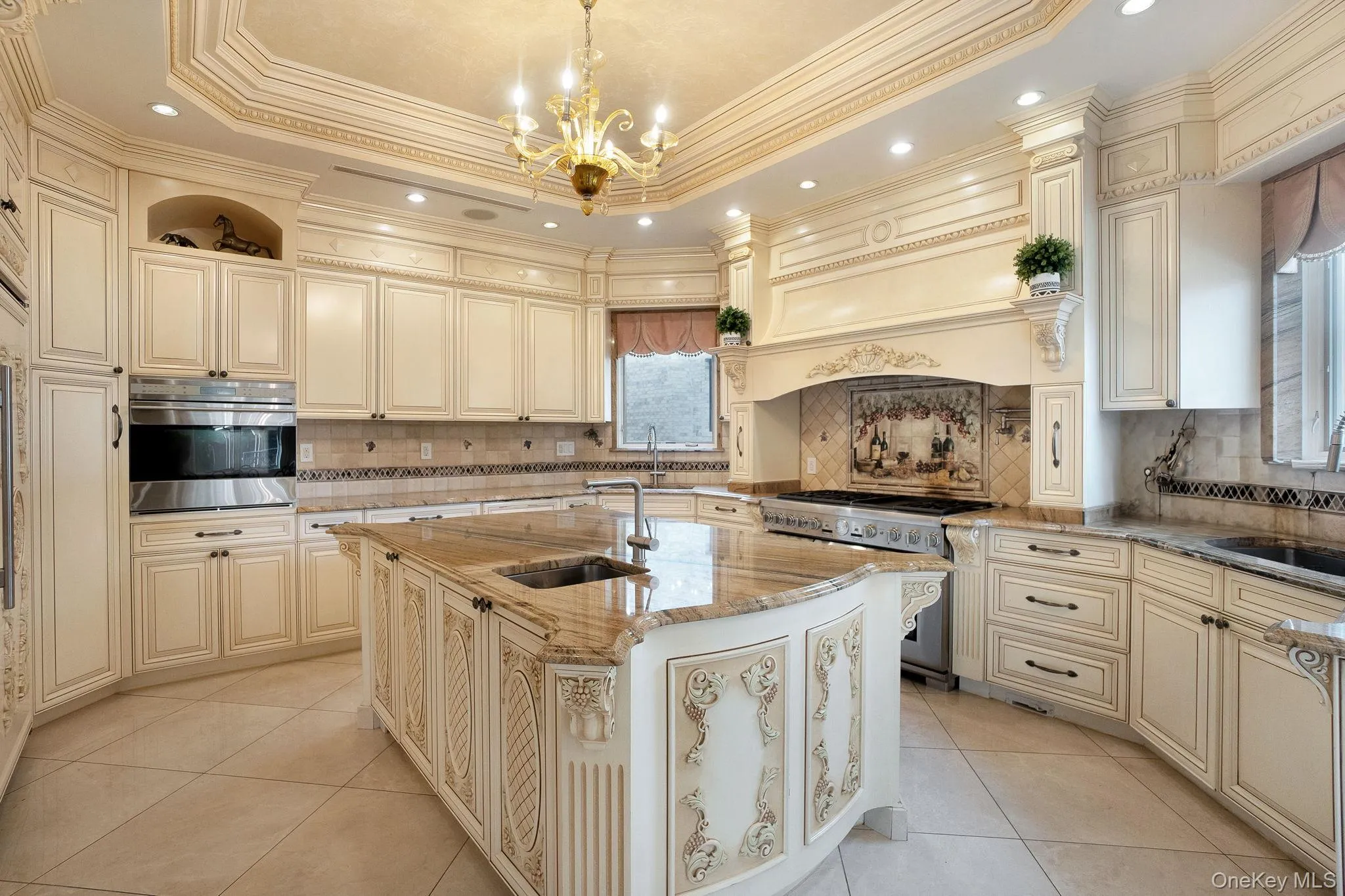 Kitchen featuring cream cabinetry, light stone counters, light tile patterned floors, recessed lighting, and stainless steel appliances Kitchen featuring cream cabinetry, light stone counters, light tile patterned floors, recessed lighting, and stainless steel appliances