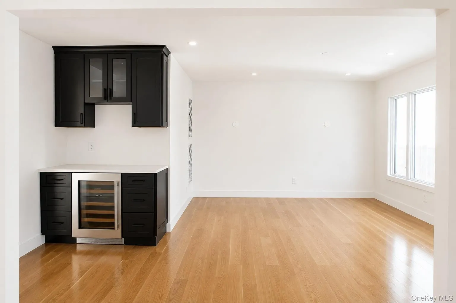 Integrated wet bar featuring dark cabinetry, a built-in beverage refrigerator, and a light-toned countertop Integrated wet bar featuring dark cabinetry, a built-in beverage refrigerator, and a light-toned countertop