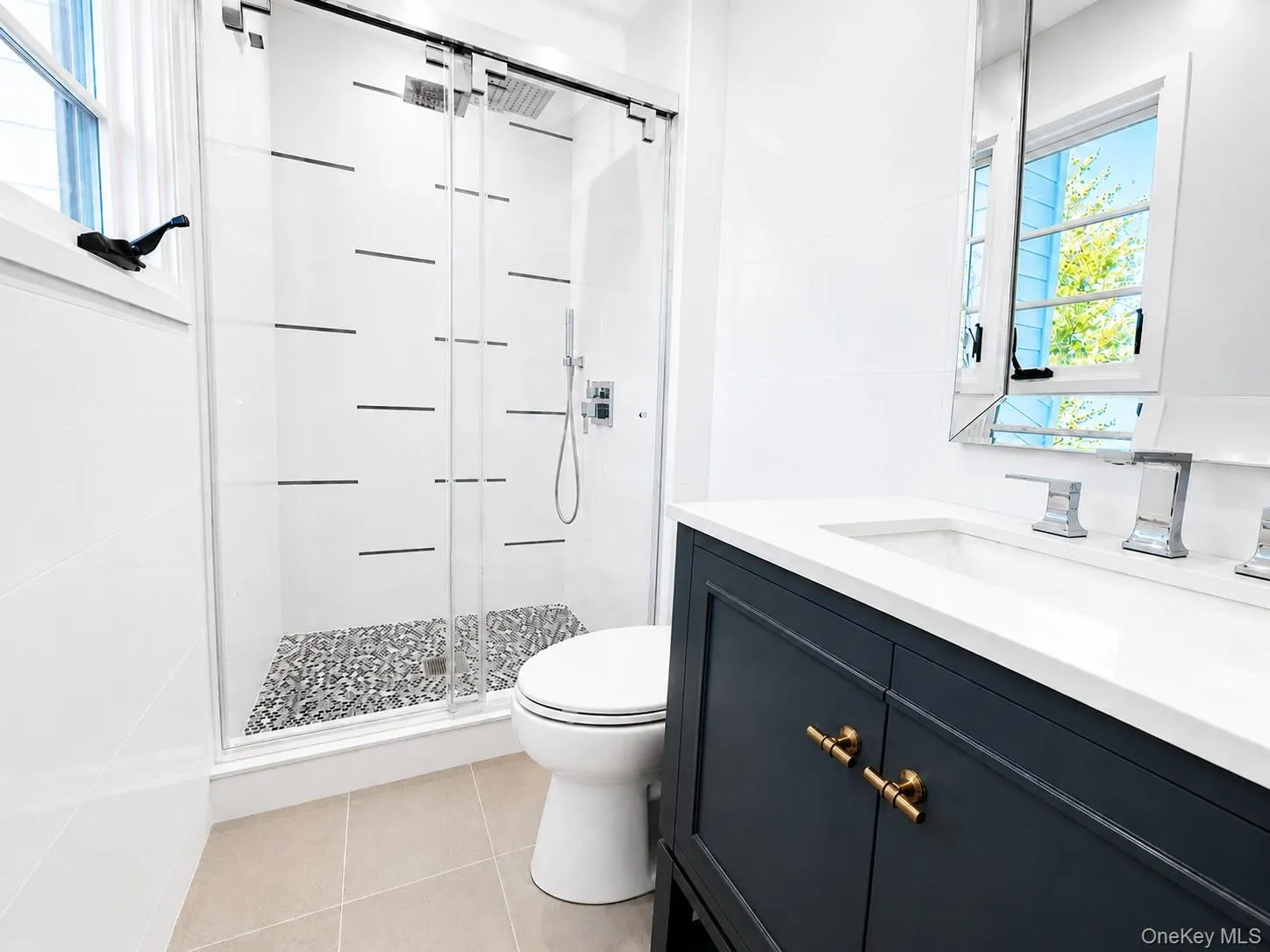 Contemporary bathroom featuring a dark blue vanity with brass hardware, a white countertop, and a double sink with chrome faucets Contemporary bathroom featuring a dark blue vanity with brass hardware, a white countertop, and a double sink with chrome faucets