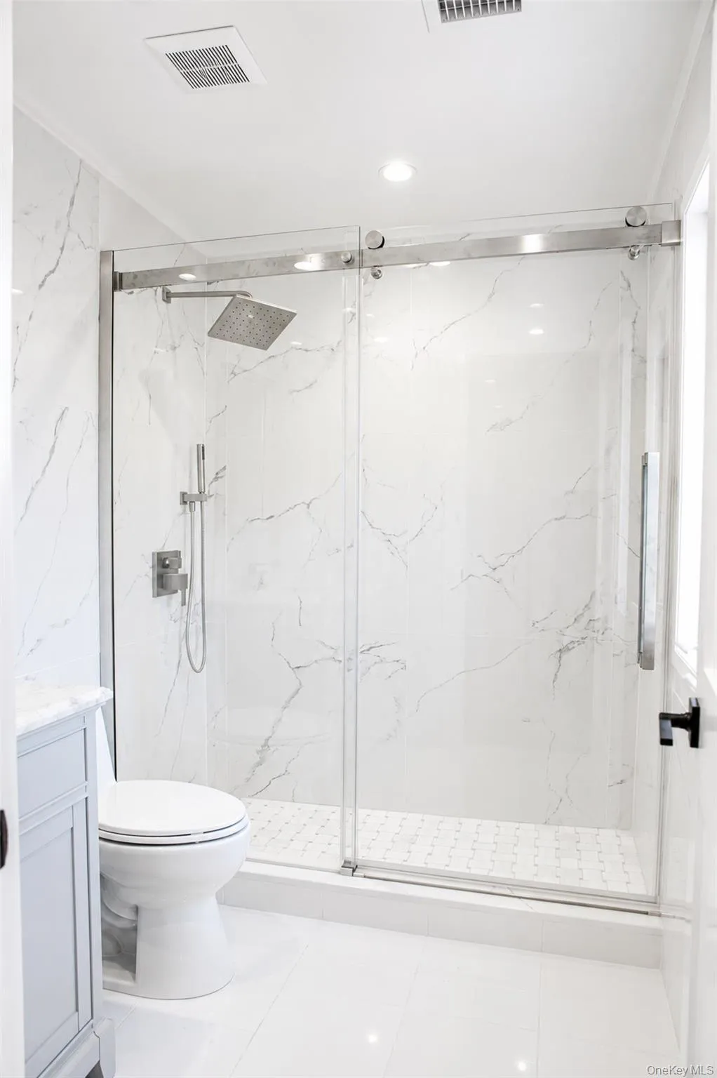 Glass-enclosed shower with a rainfall showerhead, handheld shower fixture, and a mosaic tile pan Glass-enclosed shower with a rainfall showerhead, handheld shower fixture, and a mosaic tile pan