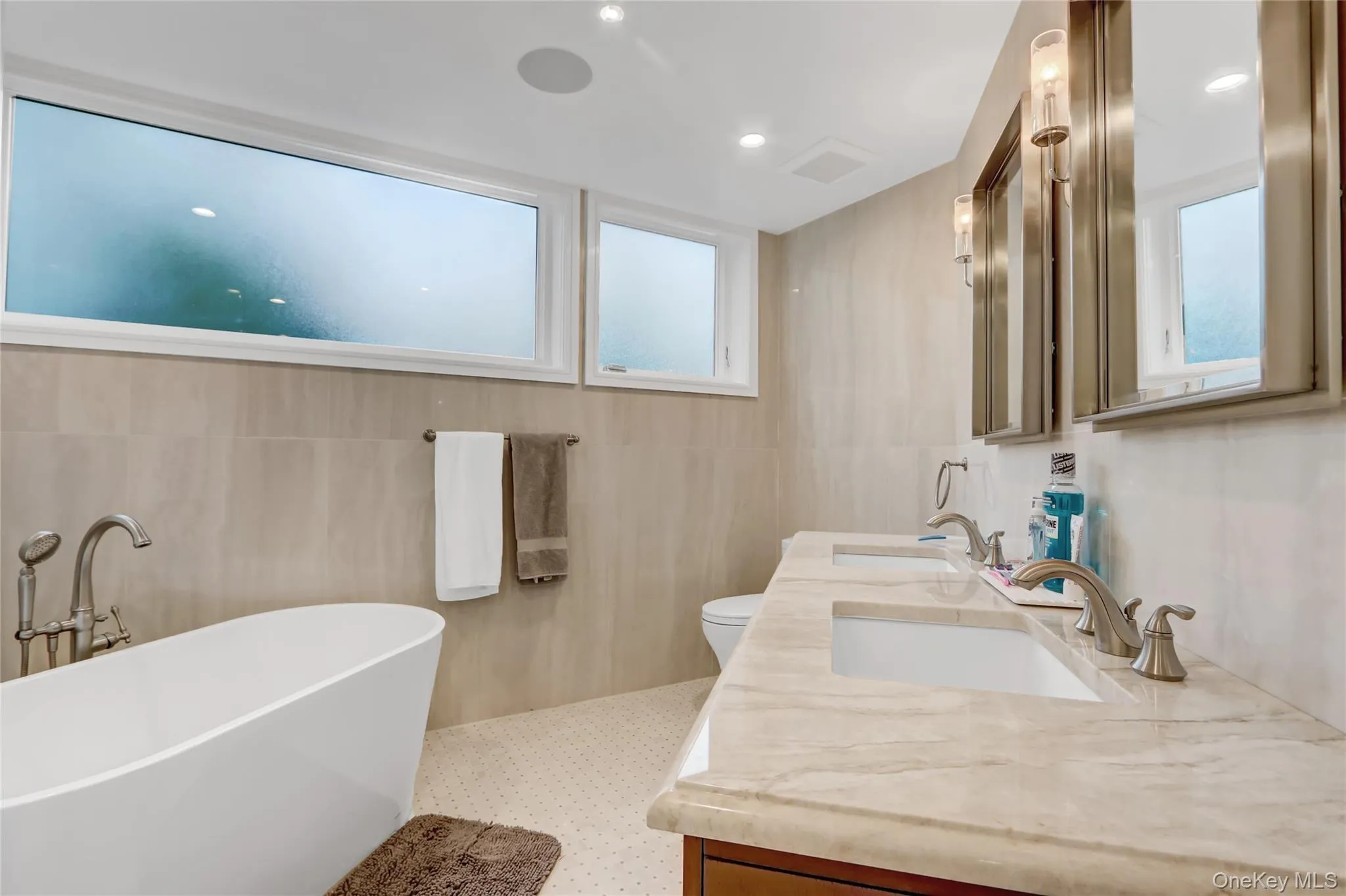 Full bath with a freestanding tub, double vanity, tile walls, and recessed lighting Full bath with a freestanding tub, double vanity, tile walls, and recessed lighting