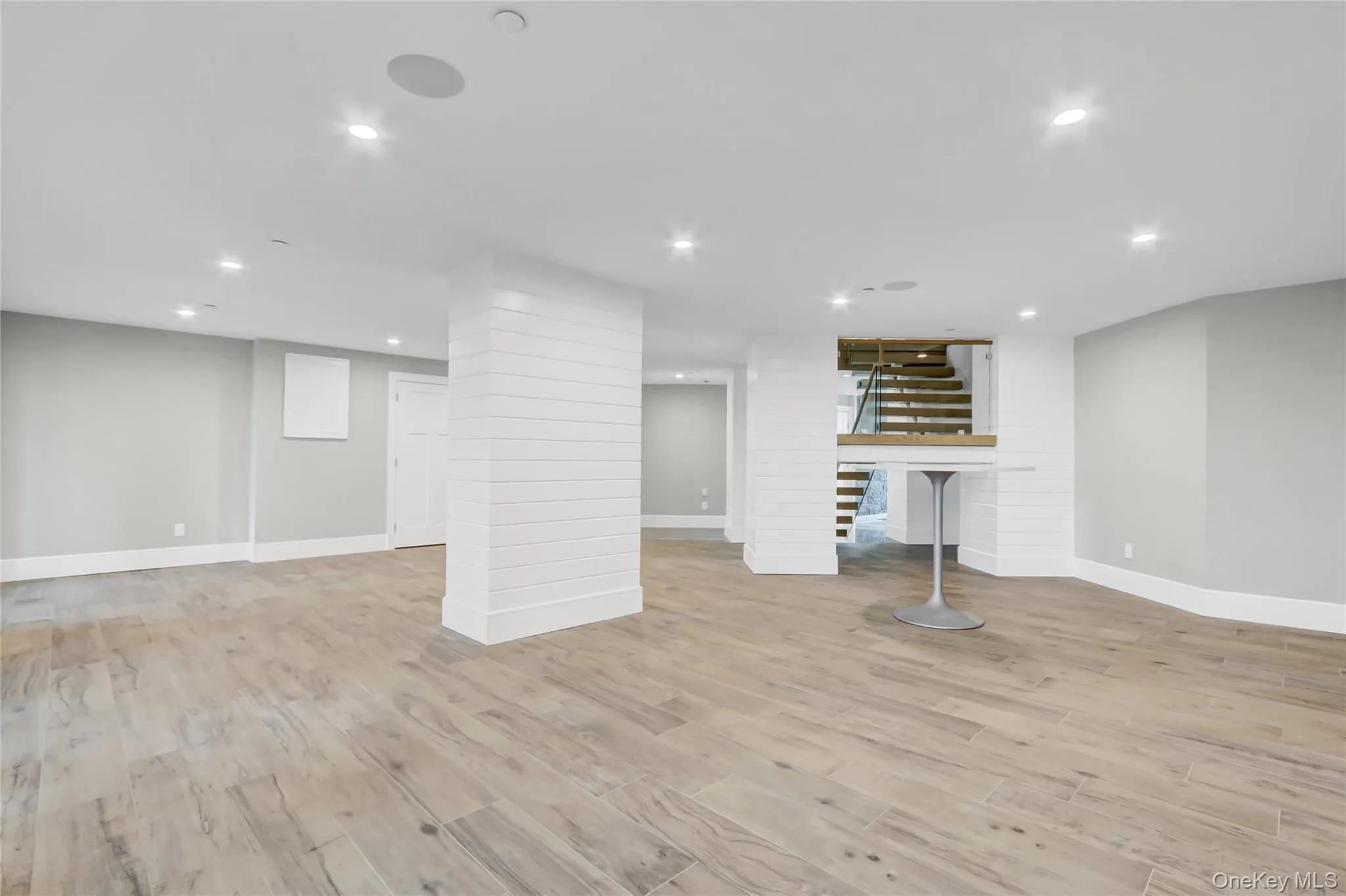 Finished ground level area with recessed lighting, light wood-style floors, and stairway Finished ground level area with recessed lighting, light wood-style floors, and stairway