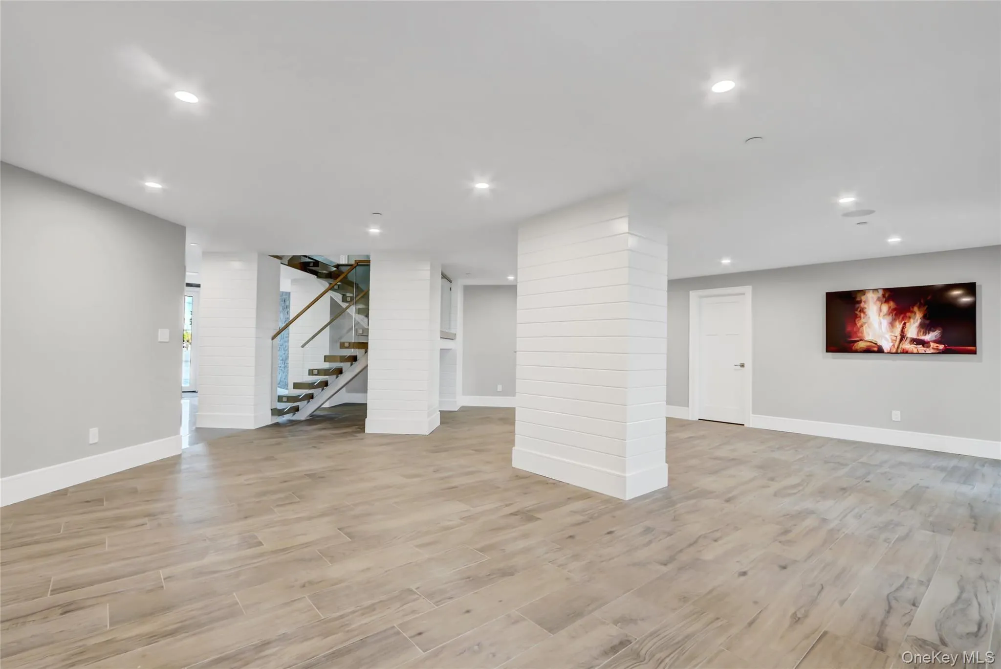 Finished ground level area featuring stairs, recessed lighting, and light wood-type flooring Finished ground level area featuring stairs, recessed lighting, and light wood-type flooring
