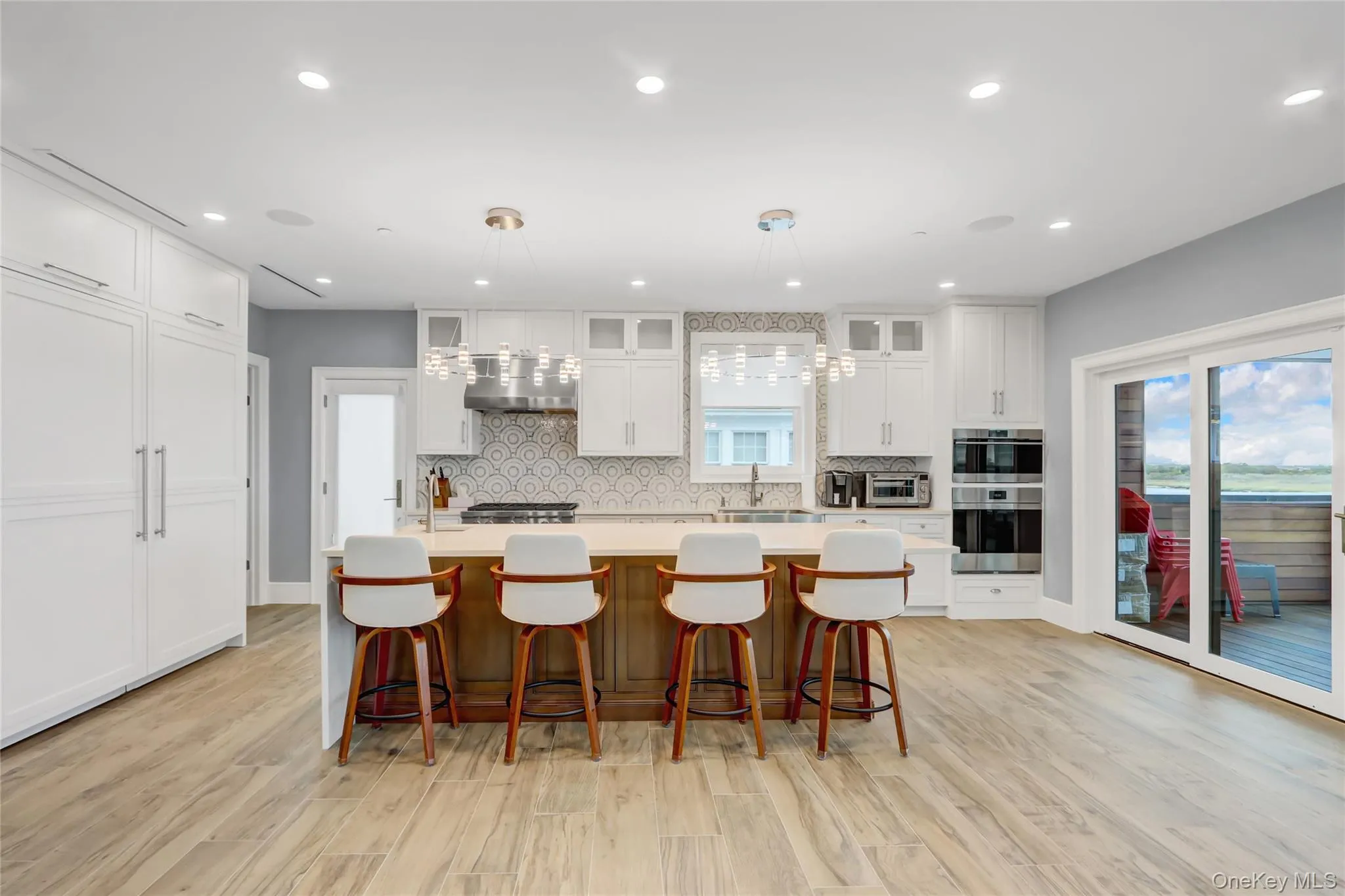 Kitchen featuring glass insert cabinets, decorative backsplash, an island with sink, white cabinetry, and a breakfast bar Kitchen featuring glass insert cabinets, decorative backsplash, an island with sink, white cabinetry, and a breakfast bar