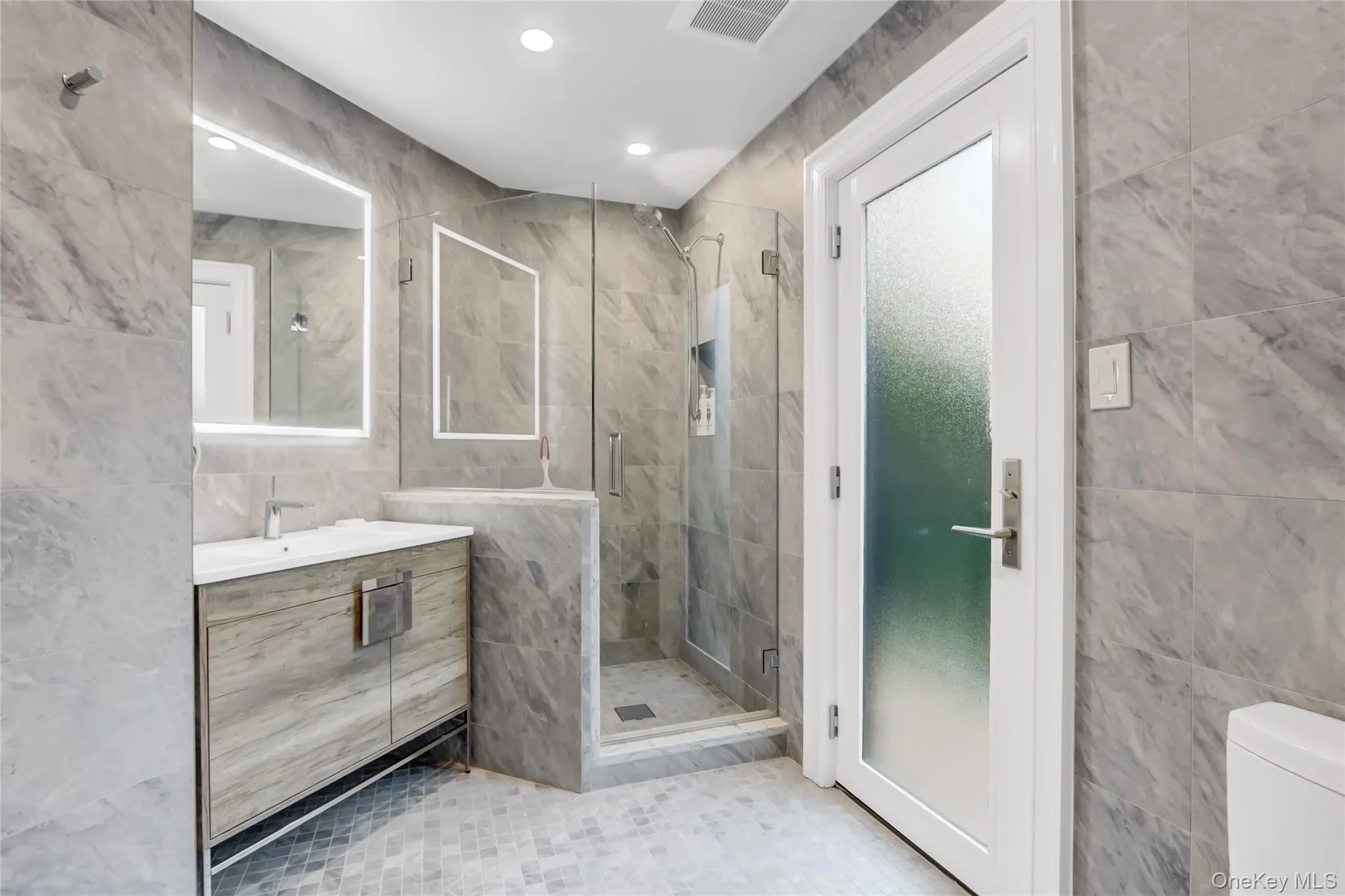 Full bathroom with tile walls, a stall shower, vanity, recessed lighting, and light tile patterned flooring Full bathroom with tile walls, a stall shower, vanity, recessed lighting, and light tile patterned flooring
