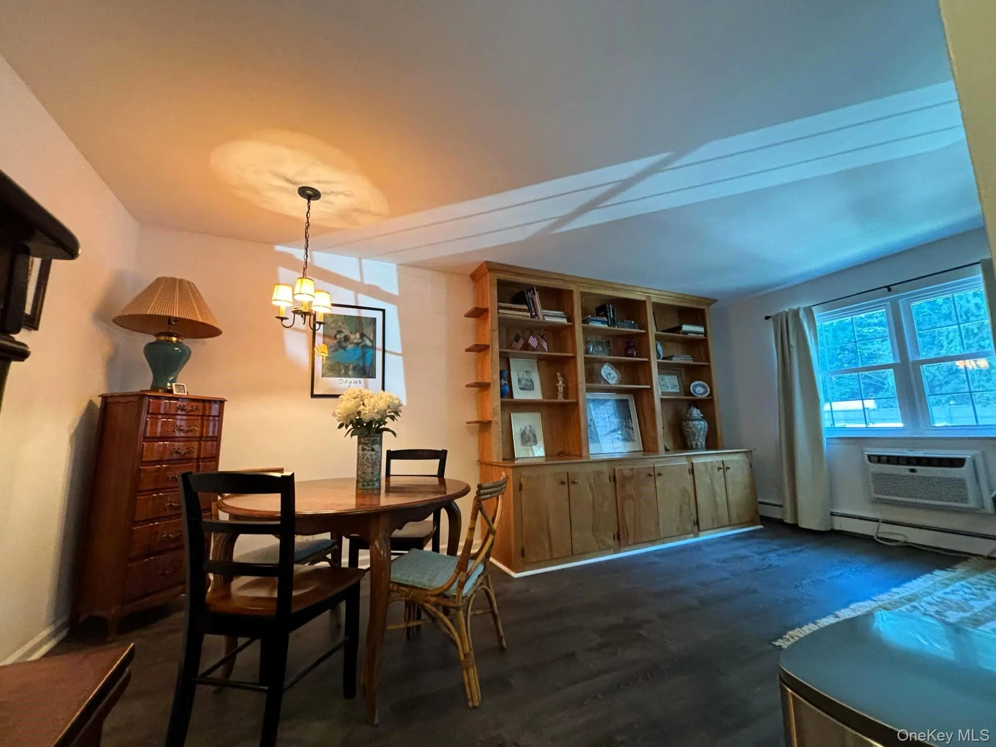 Dining space featuring dark wood-style flooring, a chandelier, and a wall mounted AC Dining space featuring dark wood-style flooring, a chandelier, and a wall mounted AC