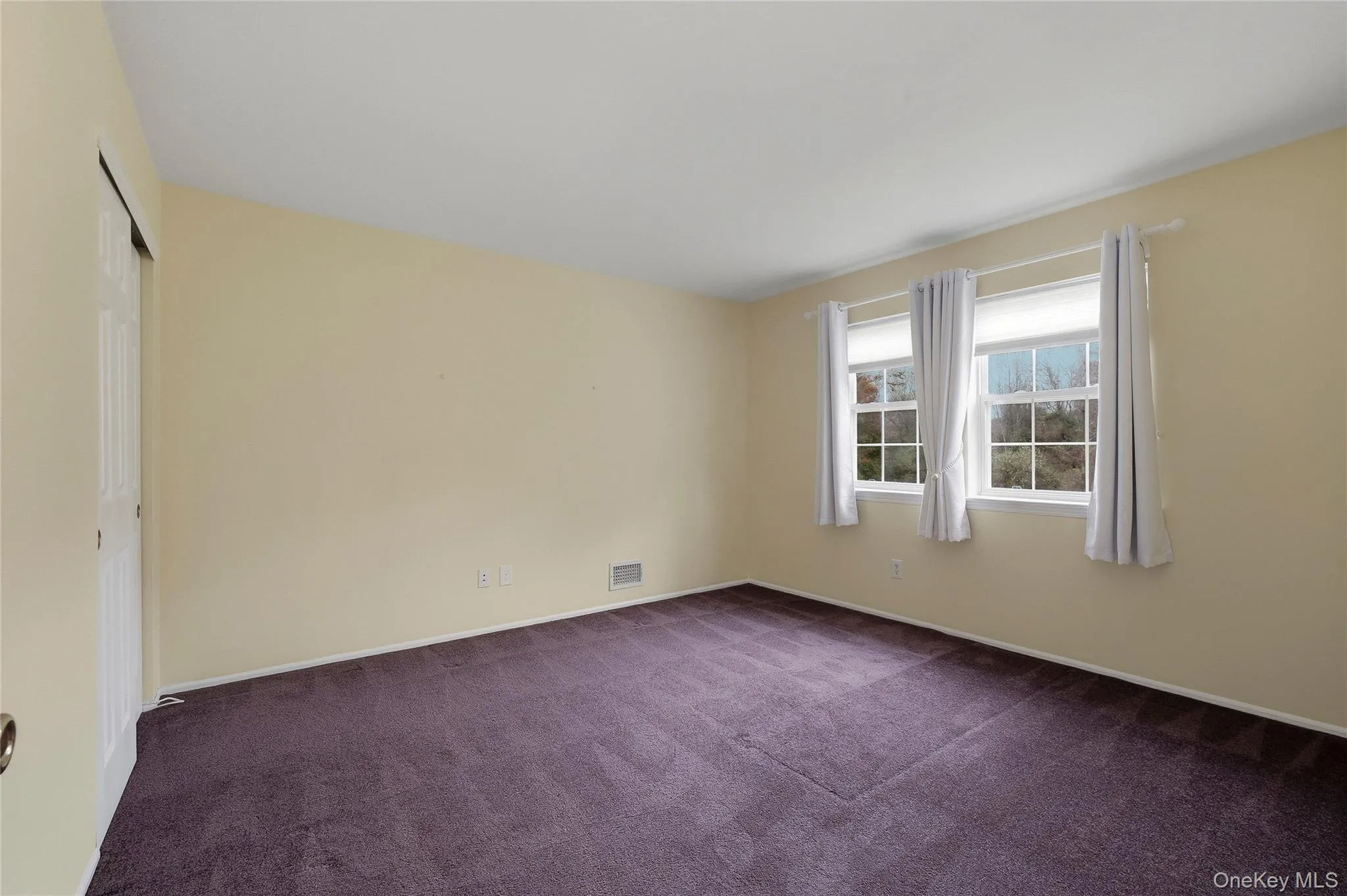 Empty room with dark colored carpet and baseboards Empty room with dark colored carpet and baseboards
