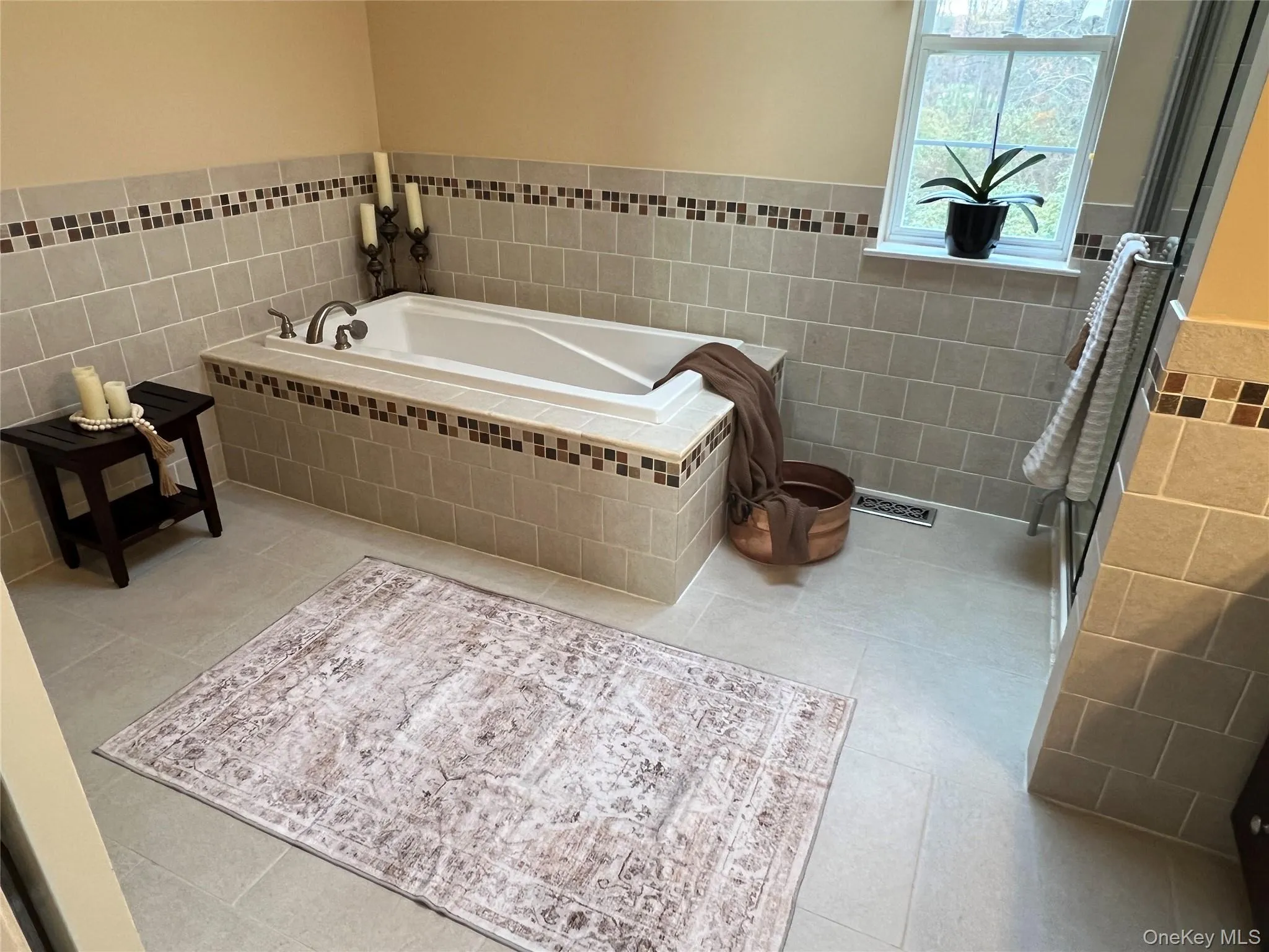 Full bathroom featuring a garden tub, tile walls, wainscoting, and light tile patterned flooring Full bathroom featuring a garden tub, tile walls, wainscoting, and light tile patterned flooring