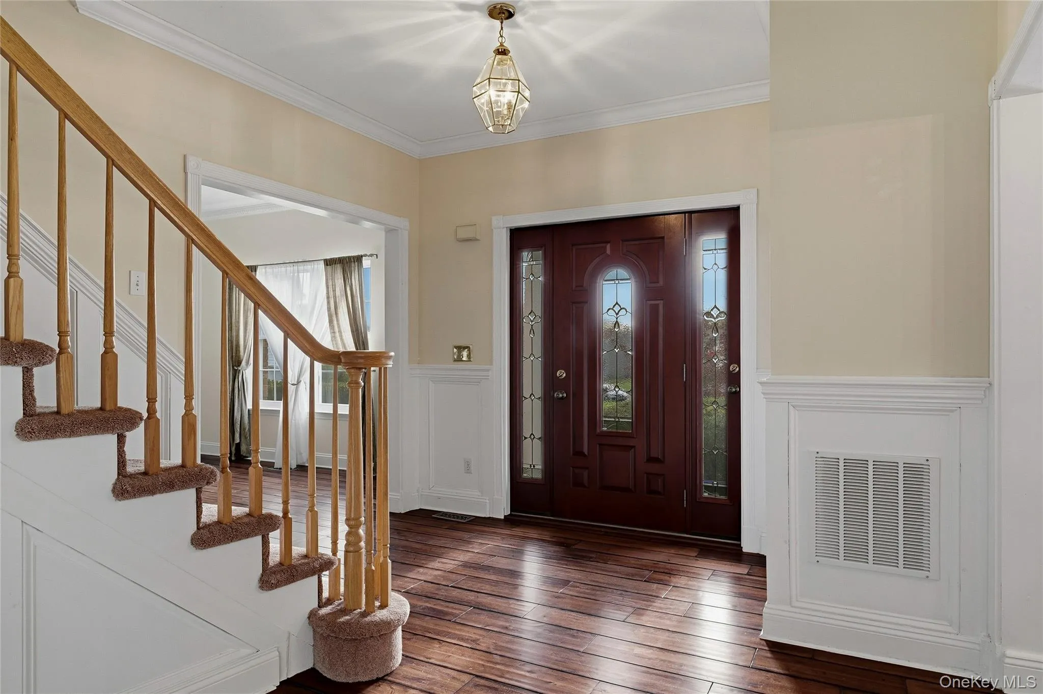 Entrance foyer with crown molding, a decorative wall, wood finished floors, a wainscoted wall, and stairway Entrance foyer with crown molding, a decorative wall, wood finished floors, a wainscoted wall, and stairway