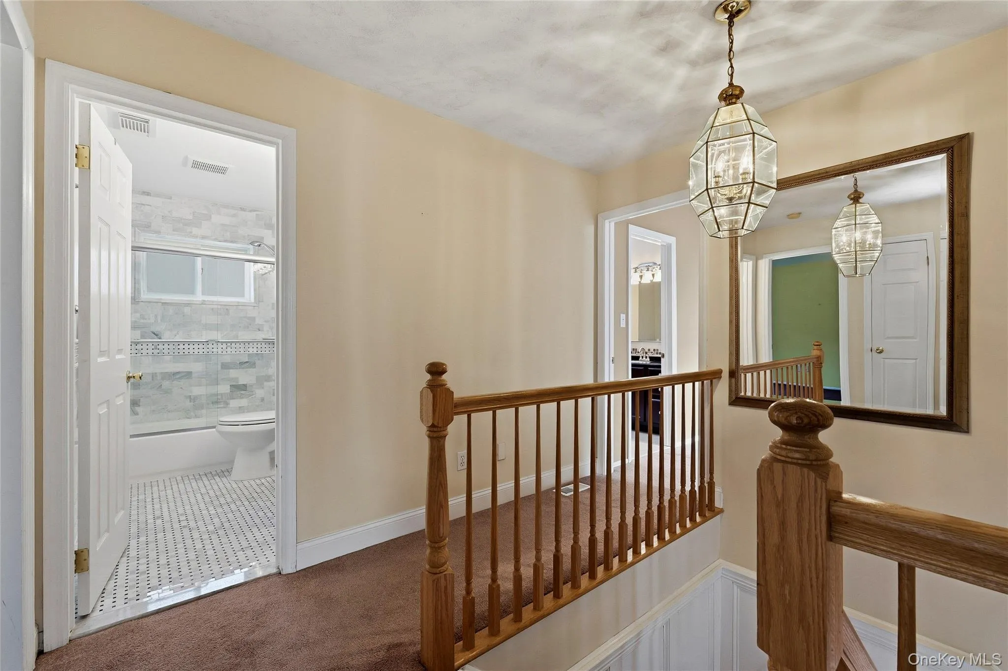 Hall with an upstairs landing, dark tile patterned flooring, and a chandelier Hall with an upstairs landing, dark tile patterned flooring, and a chandelier