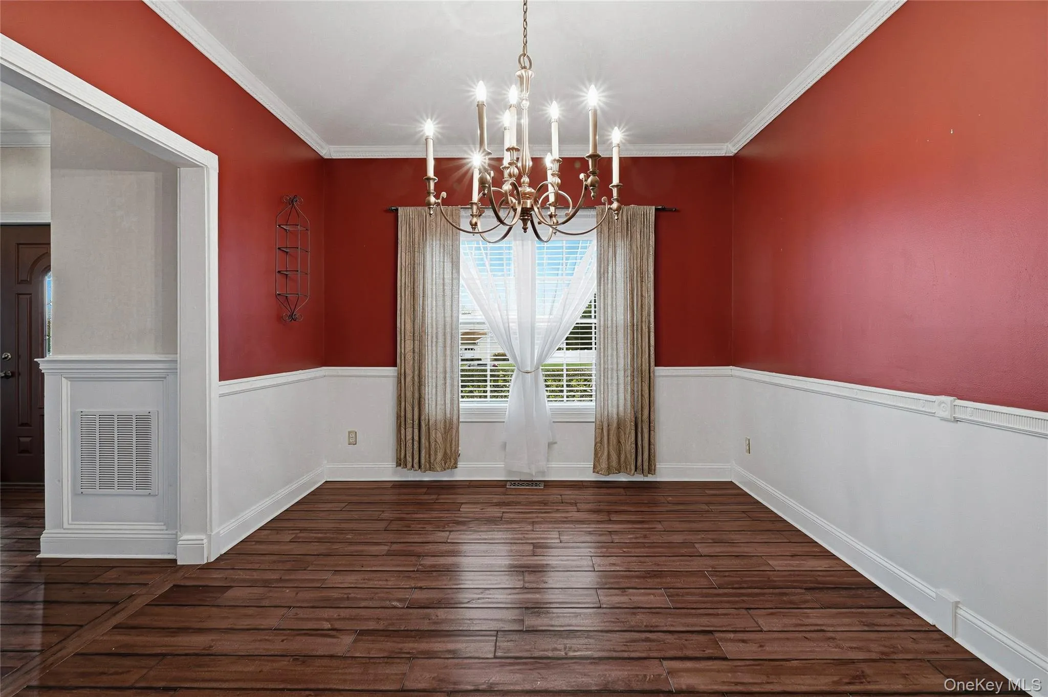 Unfurnished dining area featuring dark wood-type flooring, crown molding, a chandelier, and a wainscoted wall Unfurnished dining area featuring dark wood-type flooring, crown molding, a chandelier, and a wainscoted wall