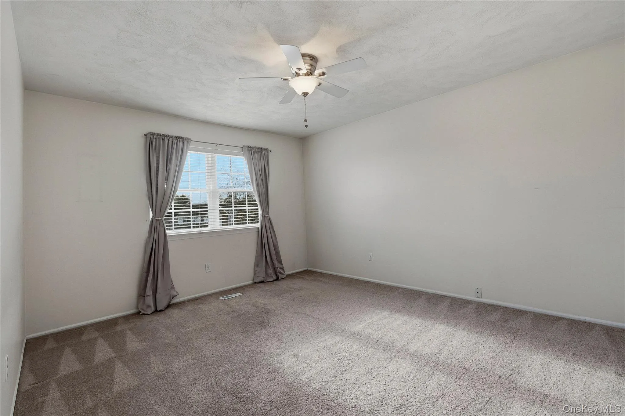 Empty room featuring light colored carpet, a ceiling fan, and a textured ceiling Empty room featuring light colored carpet, a ceiling fan, and a textured ceiling