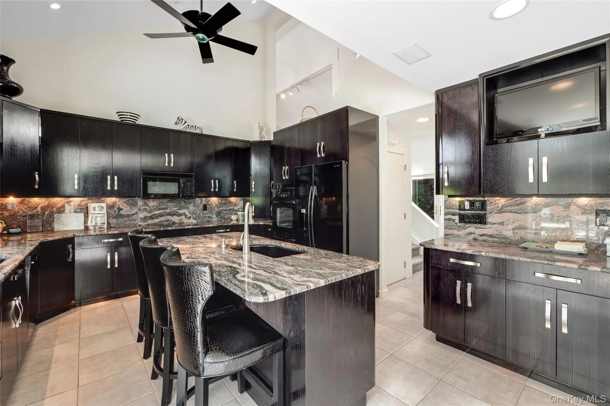Kitchen with decorative backsplash, dark stone counters, black appliances, light tile patterned floors, and recessed lighting Kitchen with decorative backsplash, dark stone counters, black appliances, light tile patterned floors, and recessed lighting