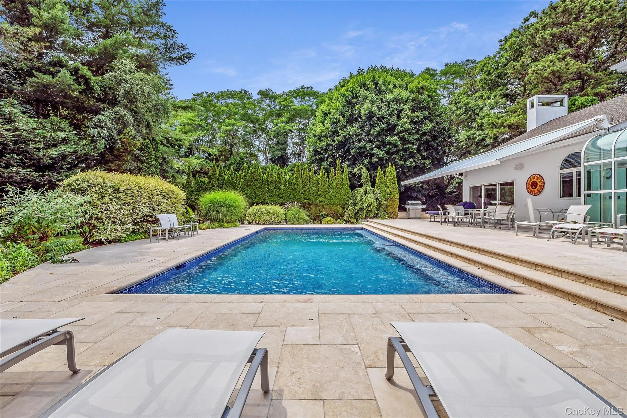 Swimming pool featuring a patio area, a wooden deck, outdoor dining space, and view of scattered trees Swimming pool featuring a patio area, a wooden deck, outdoor dining space, and view of scattered trees