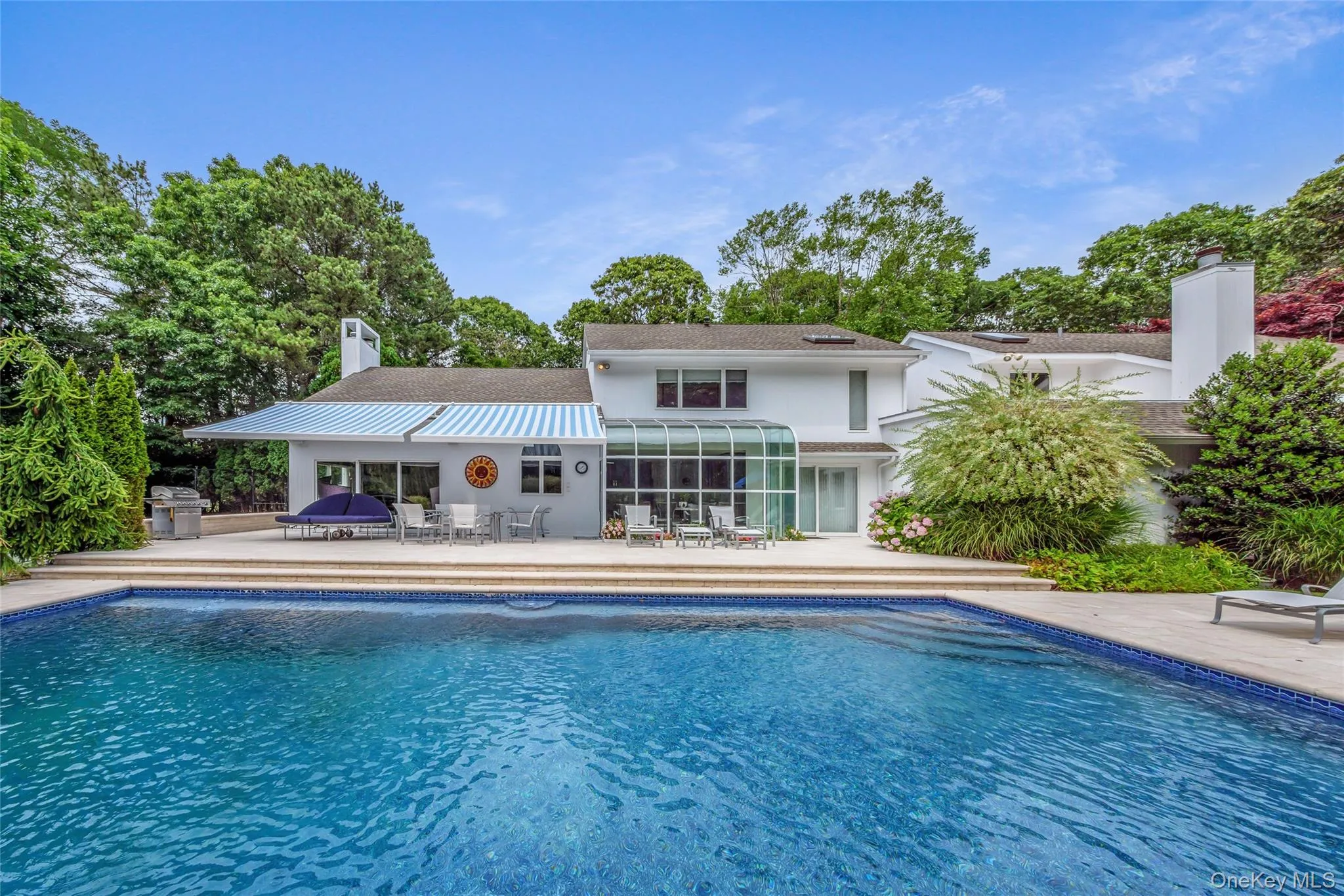 Back of house featuring a chimney, an outdoor pool, a patio, and view of wooded area Back of house featuring a chimney, an outdoor pool, a patio, and view of wooded area