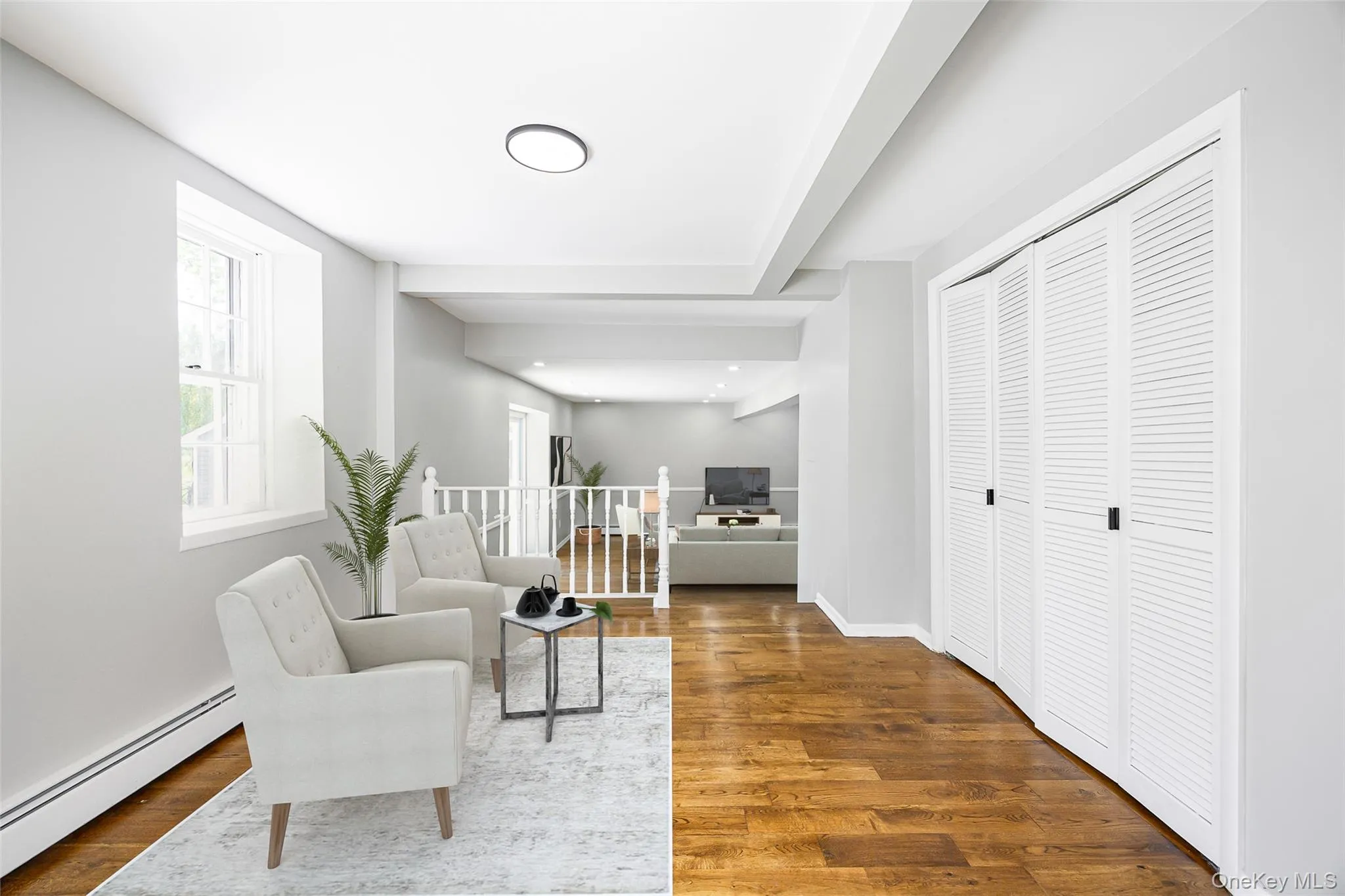 Living area with a baseboard radiator, wood finished floors, beamed ceiling, and an upstairs landing Living area with a baseboard radiator, wood finished floors, beamed ceiling, and an upstairs landing