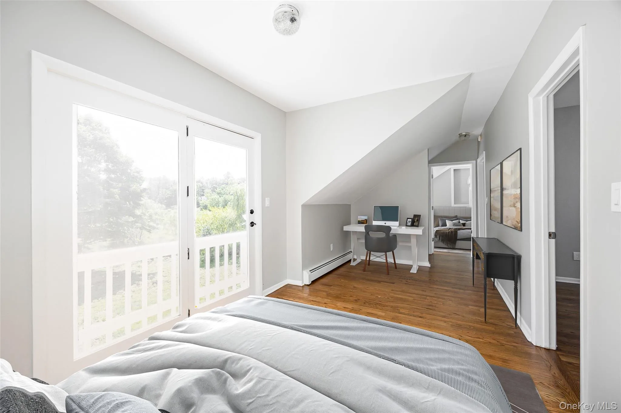 Bedroom with a desk, wood finished floors, a baseboard radiator, and access to outside Bedroom with a desk, wood finished floors, a baseboard radiator, and access to outside