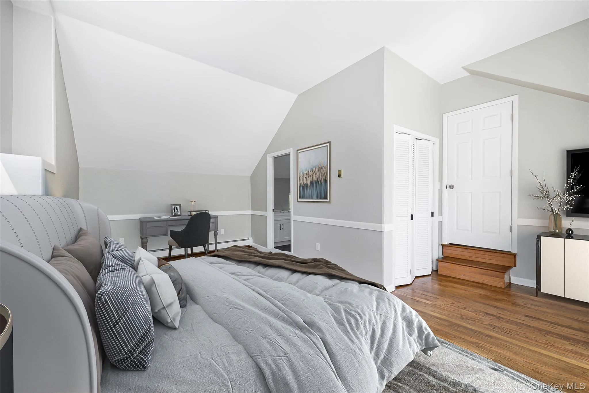Bedroom with a desk, lofted ceiling, wood finished floors, and baseboard heating Bedroom with a desk, lofted ceiling, wood finished floors, and baseboard heating