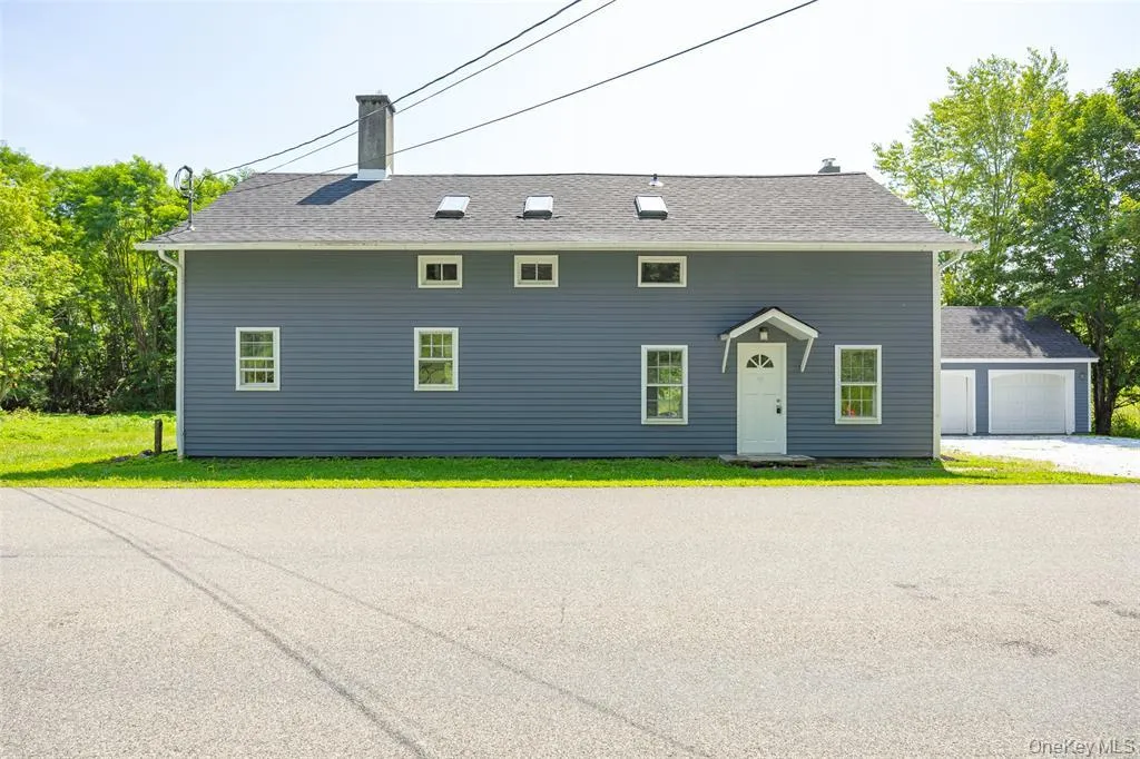 View of front of property with a front yard, a chimney, a garage, and roof with shingles View of front of property with a front yard, a chimney, a garage, and roof with shingles
