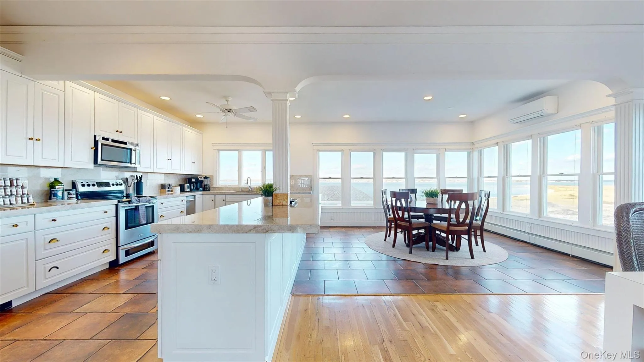 Kitchen featuring ornate columns, white cabinetry, appliances with stainless steel finishes, a baseboard heating unit, and backsplash Kitchen featuring ornate columns, white cabinetry, appliances with stainless steel finishes, a baseboard heating unit, and backsplash
