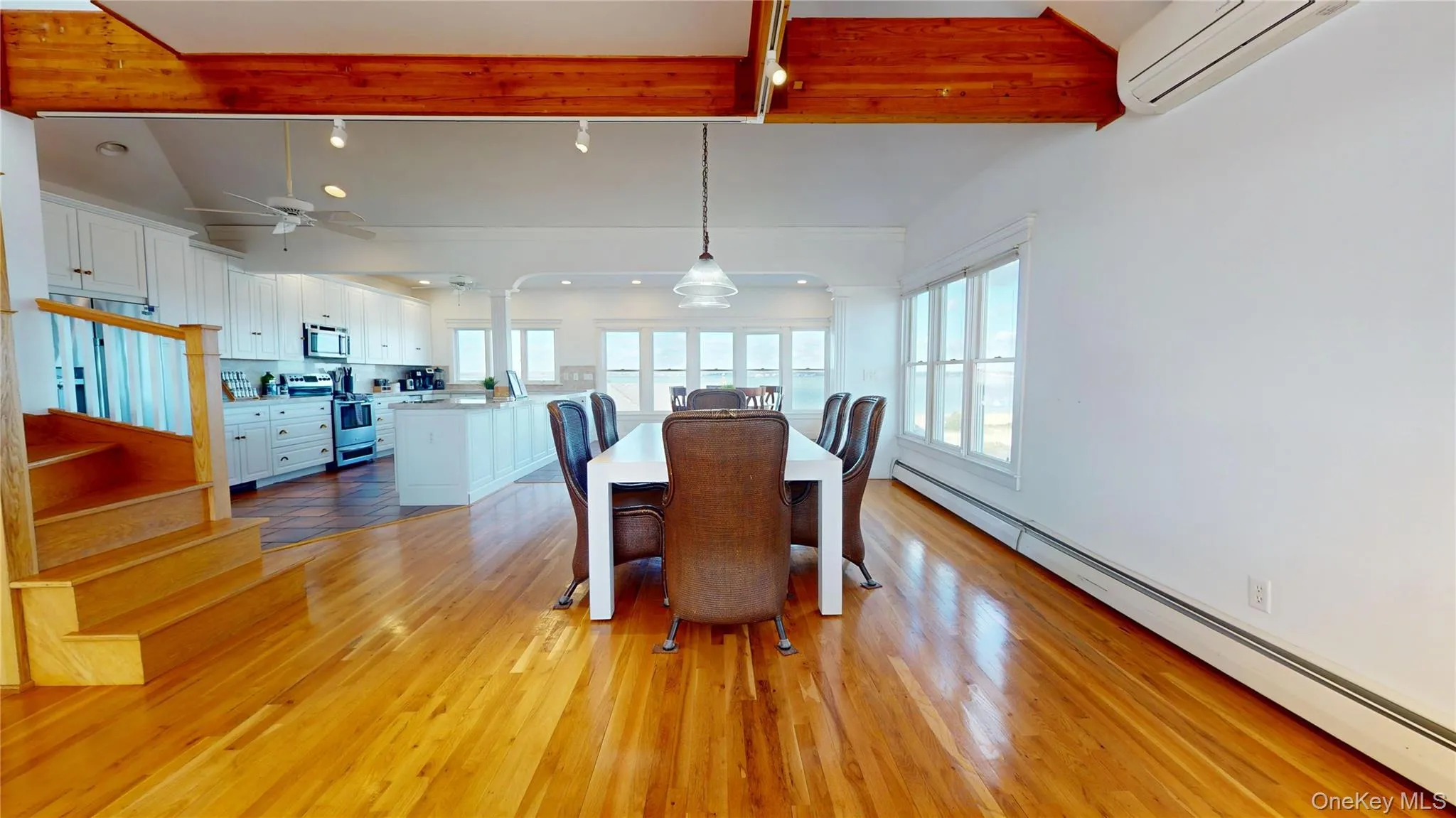 Dining area featuring a baseboard radiator, an AC wall unit, stairway, light wood-type flooring, and vaulted ceiling Dining area featuring a baseboard radiator, an AC wall unit, stairway, light wood-type flooring, and vaulted ceiling