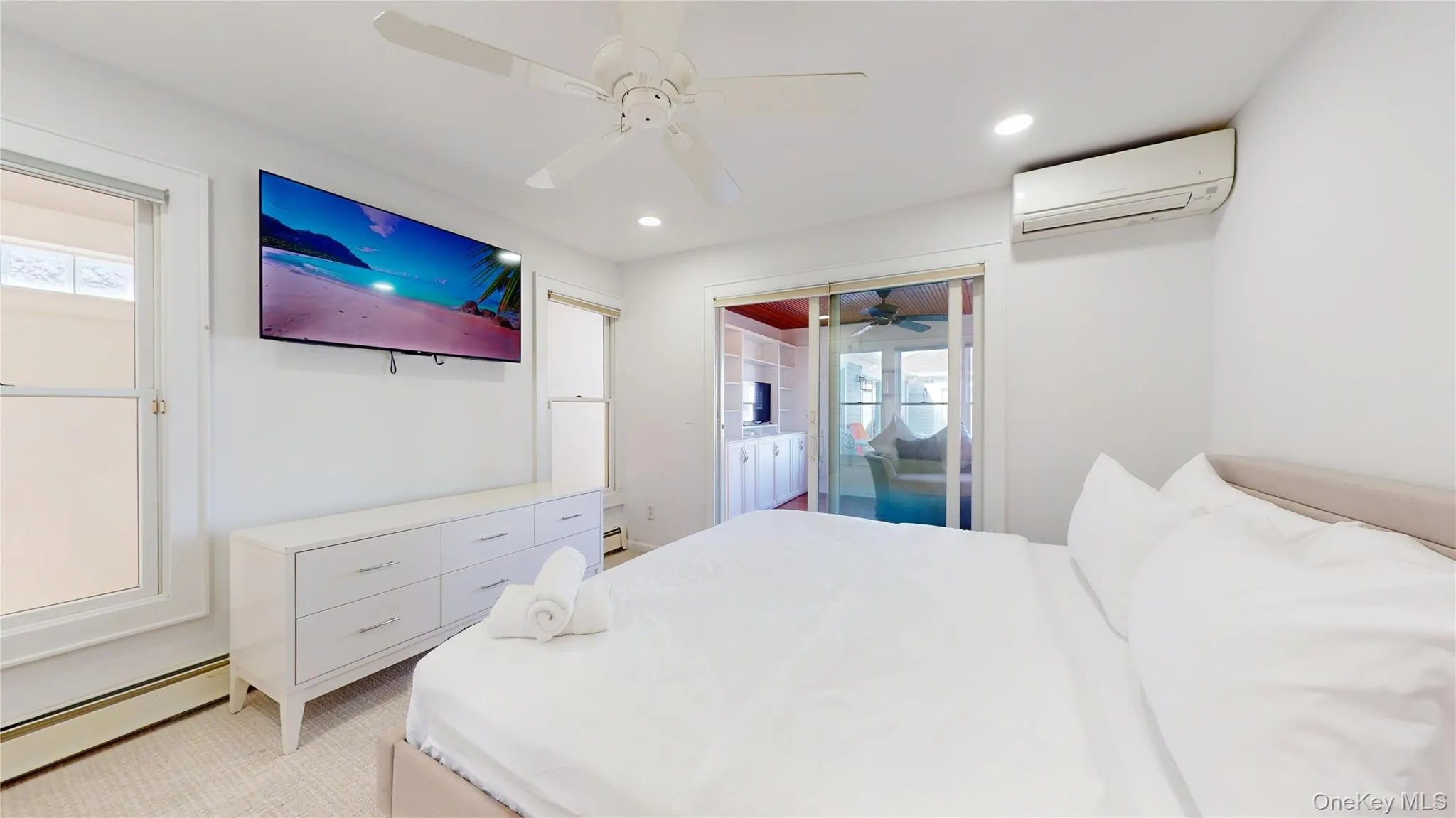 Bedroom featuring a baseboard heating unit, ceiling fan, a wall unit AC, multiple windows, and recessed lighting Bedroom featuring a baseboard heating unit, ceiling fan, a wall unit AC, multiple windows, and recessed lighting