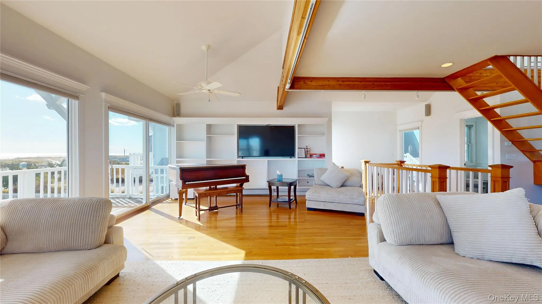Living area with wood finished floors, a ceiling fan, and stairs Living area with wood finished floors, a ceiling fan, and stairs