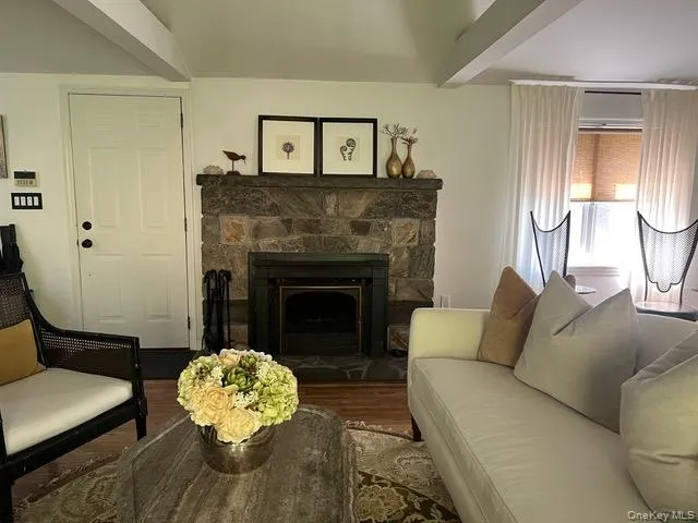 Living area with beamed ceiling, a stone fireplace, and wood finished floors Living area with beamed ceiling, a stone fireplace, and wood finished floors