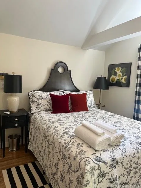 Bedroom featuring dark wood-style flooring and vaulted ceiling Bedroom featuring dark wood-style flooring and vaulted ceiling