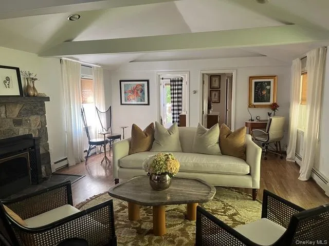 Living area with wood finished floors, a fireplace, an office area, and a baseboard heating unit Living area with wood finished floors, a fireplace, an office area, and a baseboard heating unit