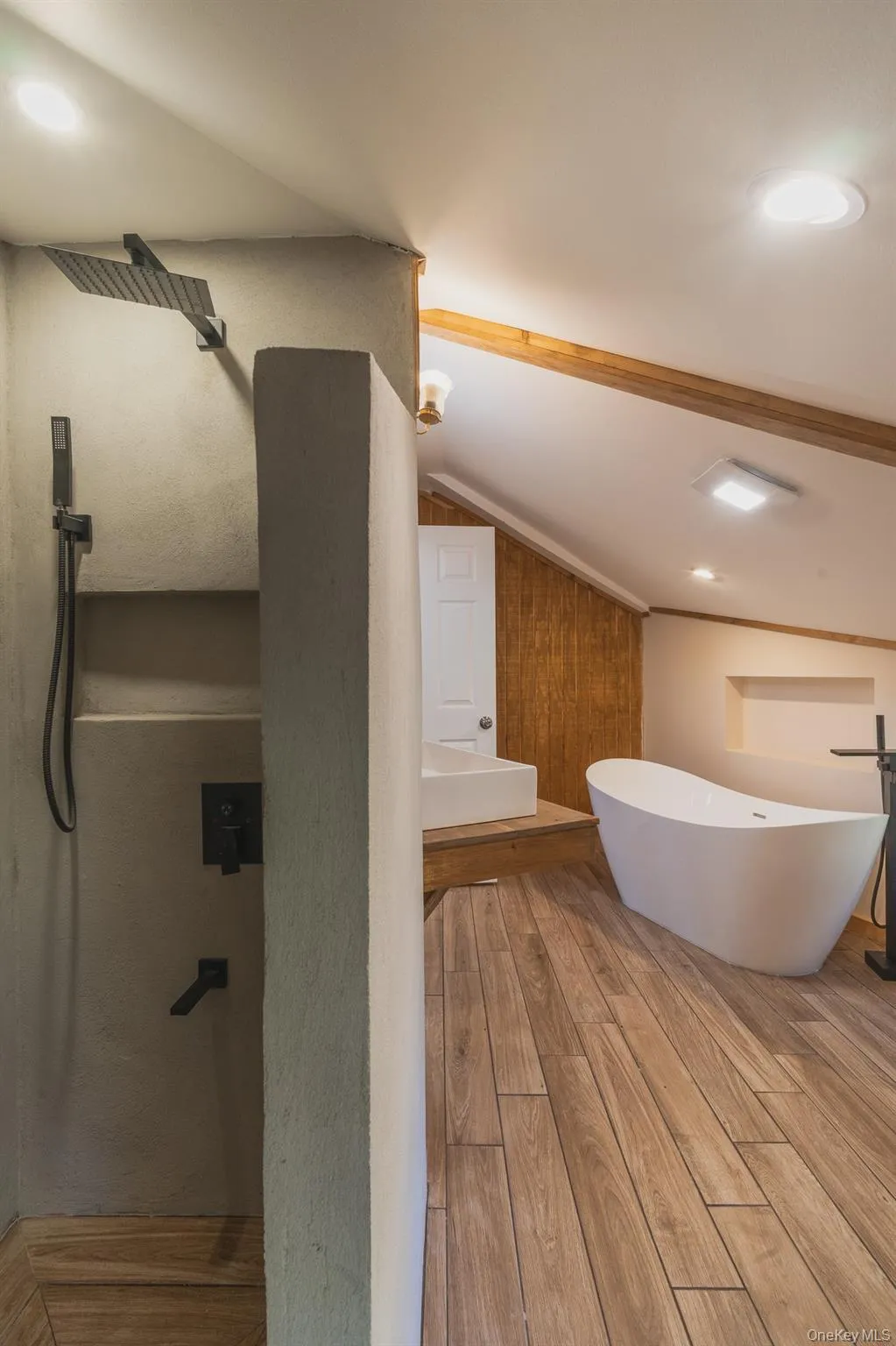 Bathroom featuring lofted ceiling, wood finished floors, and a freestanding bath Bathroom featuring lofted ceiling, wood finished floors, and a freestanding bath